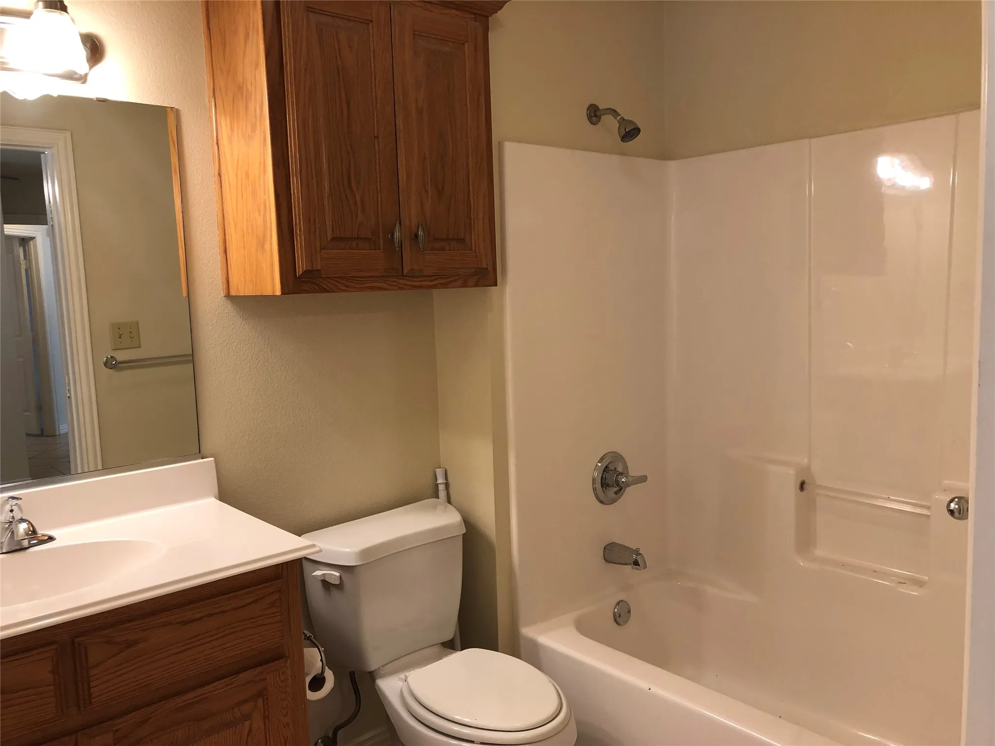 Bathroom featuring a vanity with wood-finish cabinetry, a white countertop with integrated sink, and a chrome faucet