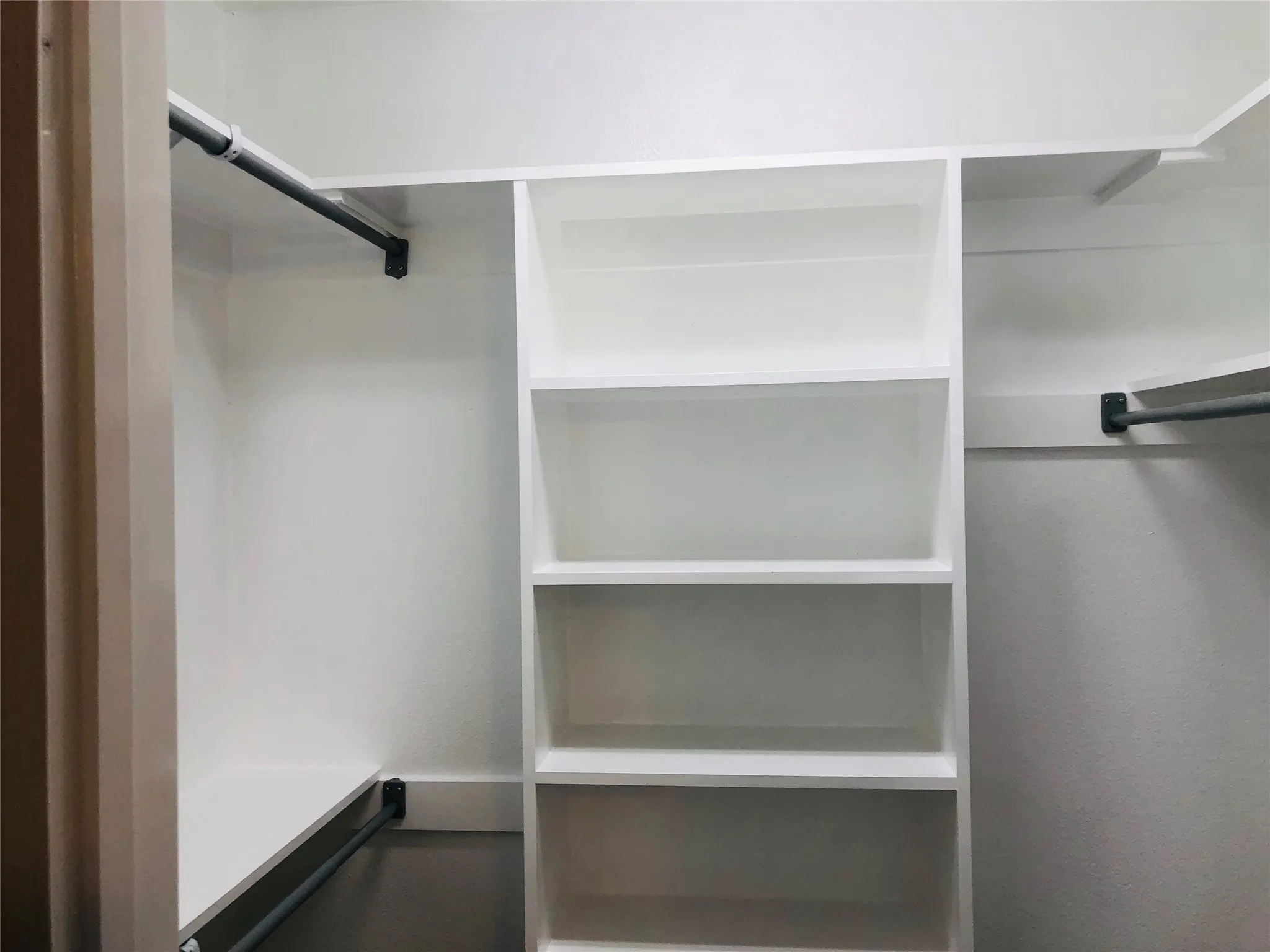 Built-in closet system featuring multiple white shelving units and clothes rods