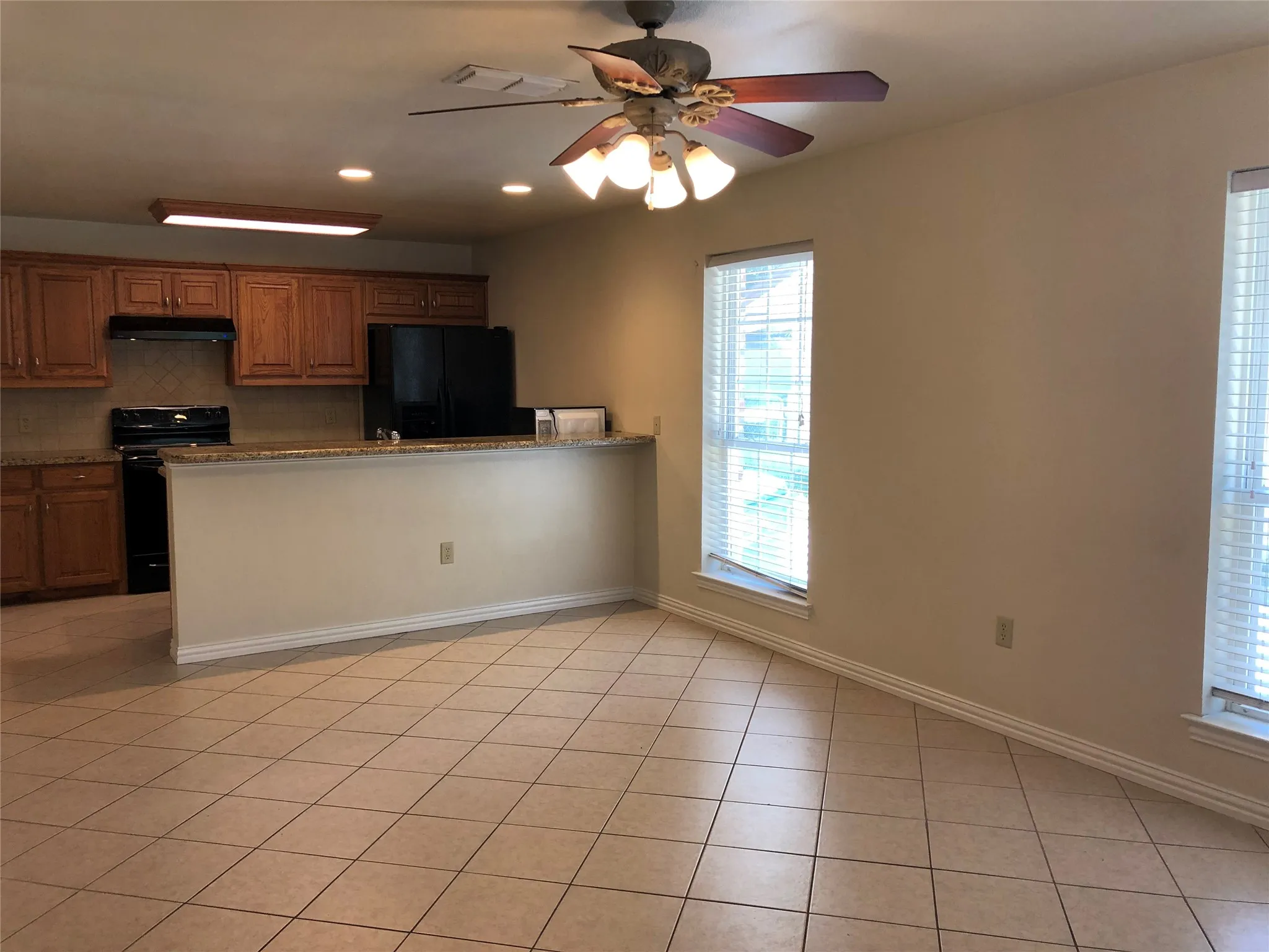 Kitchen and dining area featuring warm wood cabinetry, granite countertops, tile flooring, and multiple windows