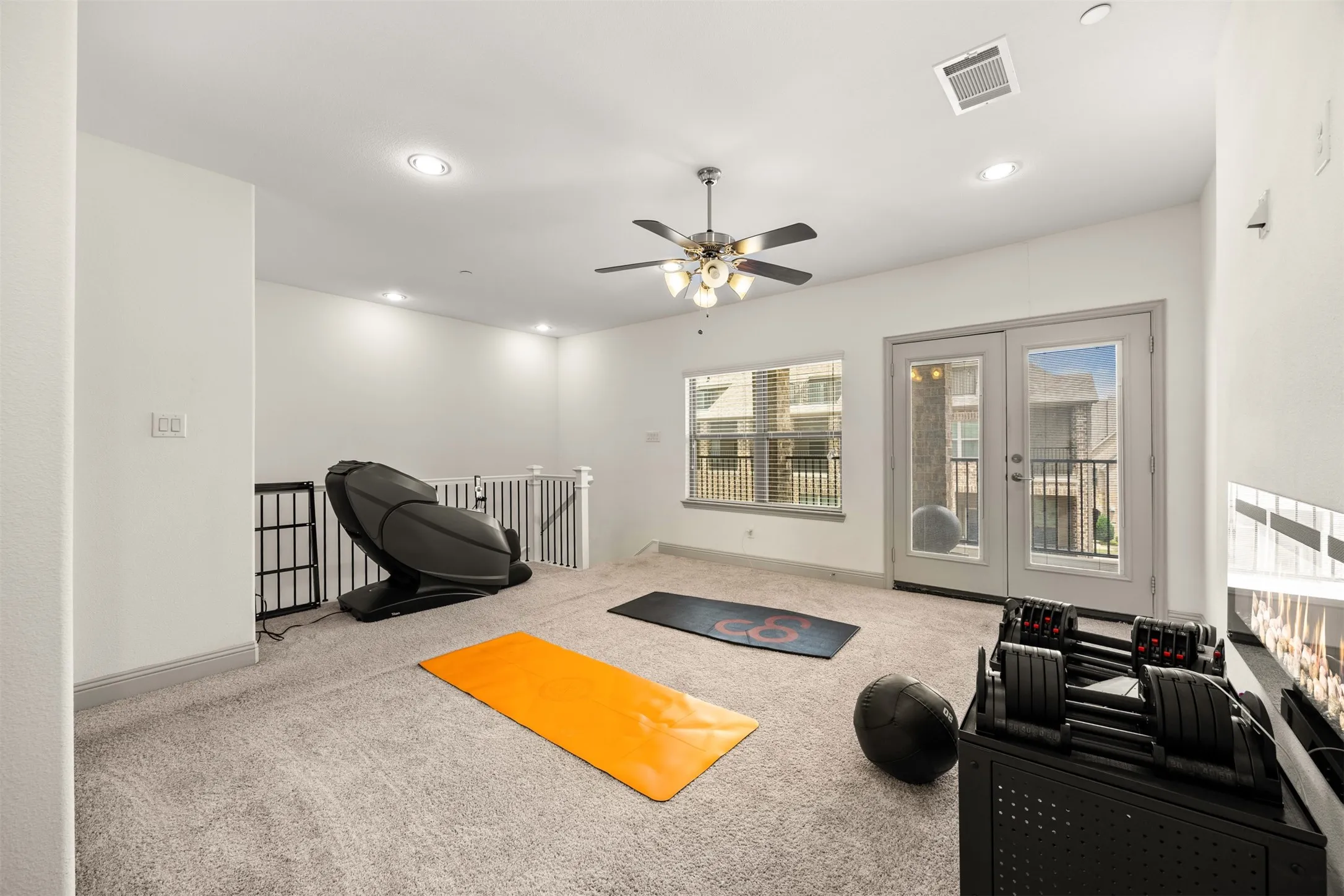 Carpeted open loft area featuring a ceiling fan, recessed lighting, and a window with balcony access