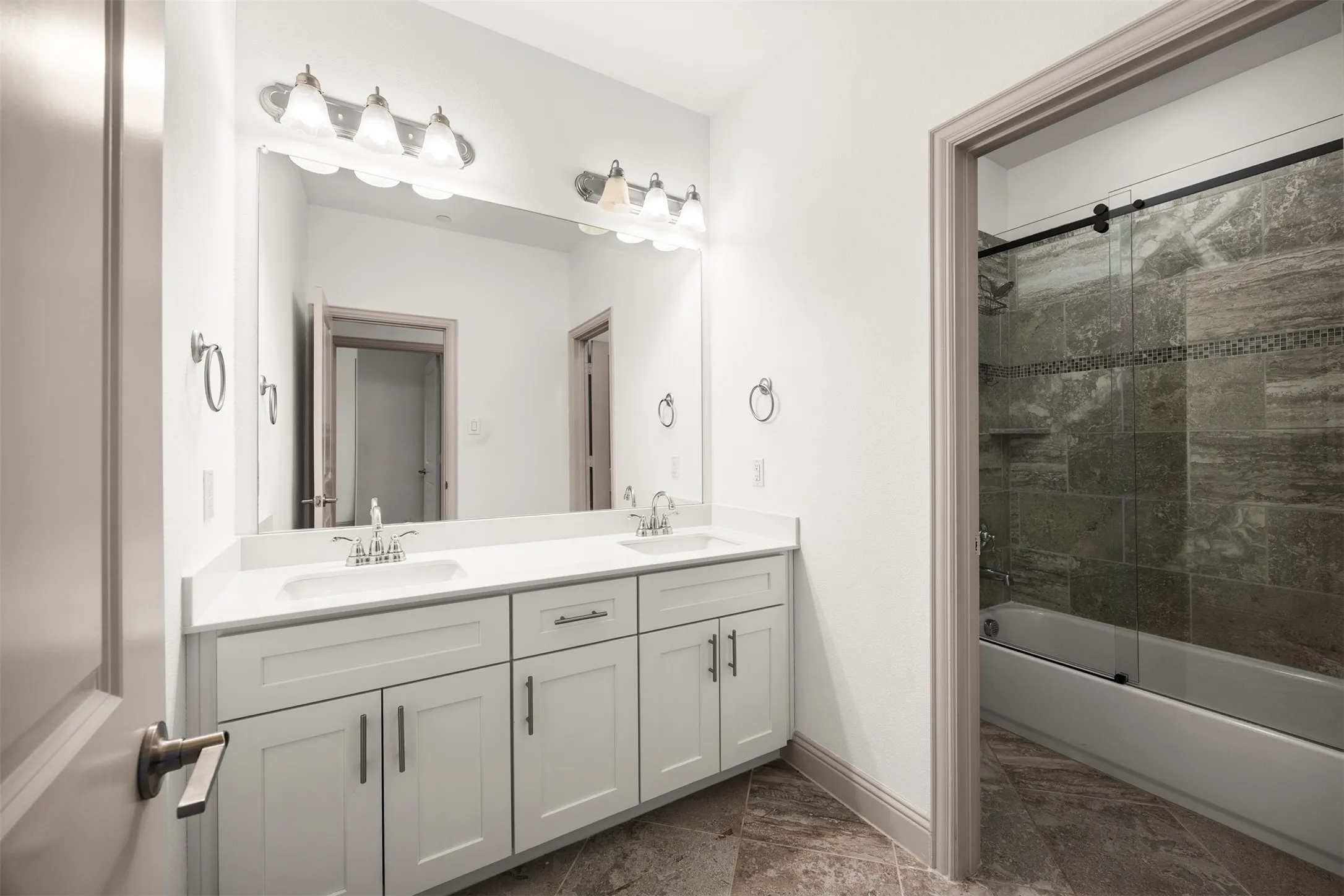 Bathroom featuring a dual vanity with white cabinetry, white countertops, chrome fixtures, and a large wall-mounted mirror