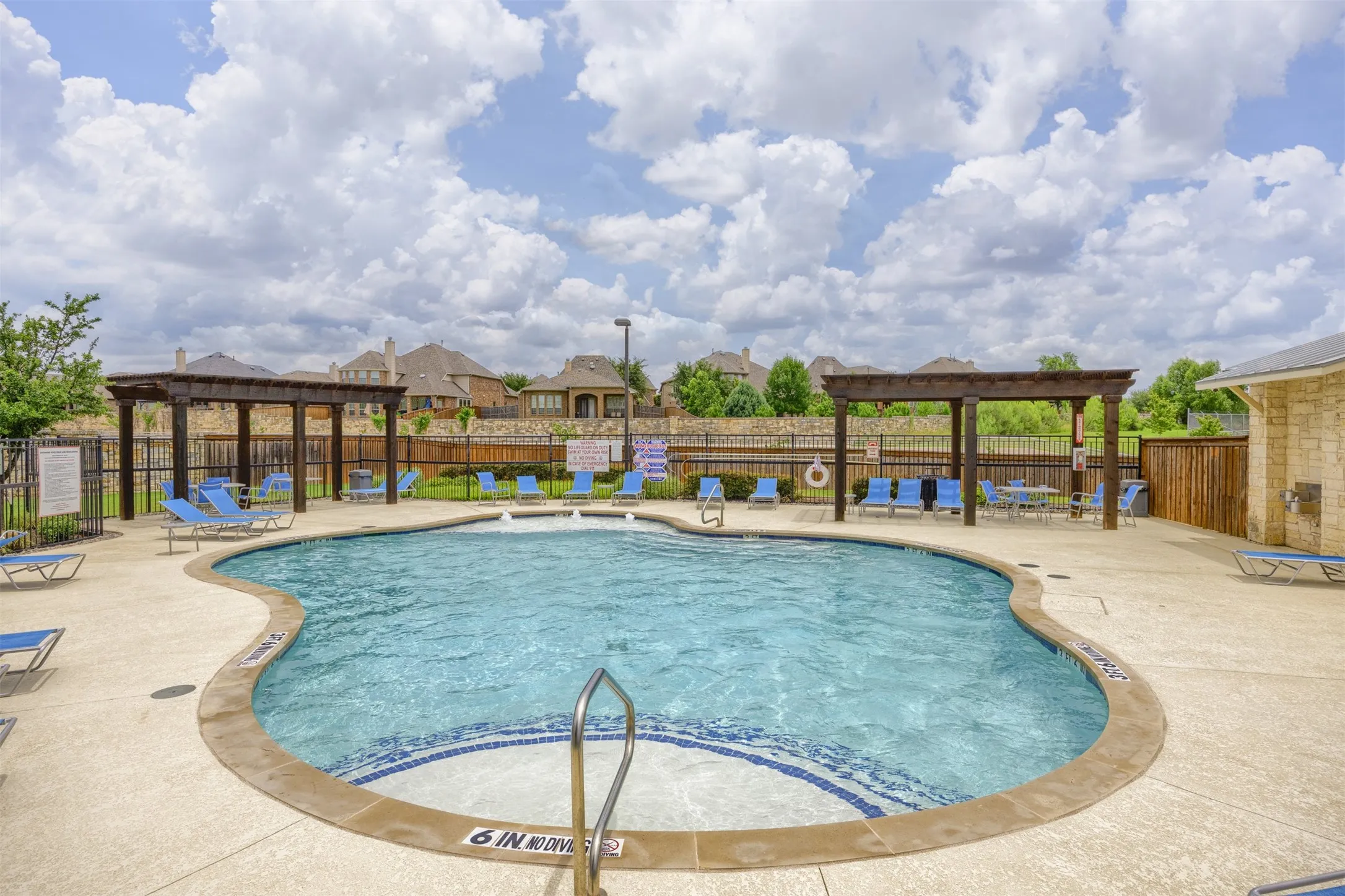 Freeform swimming pool with integrated spa, surrounded by a concrete deck