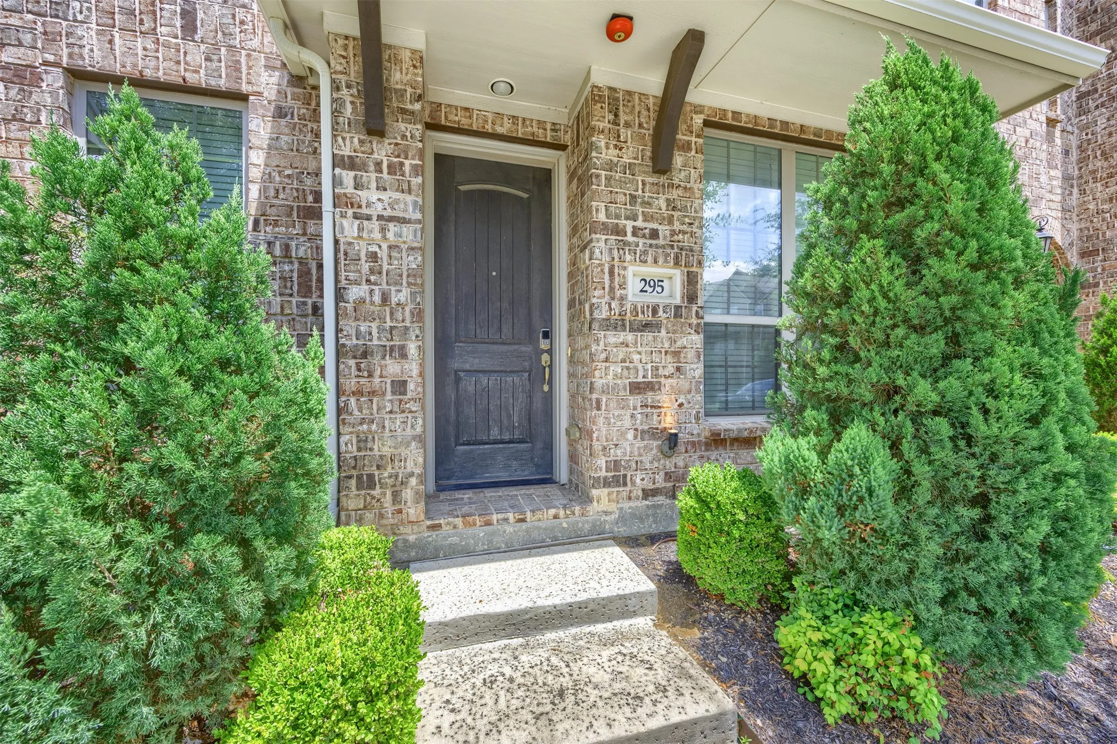 Brick facade entry featuring a paneled door, decorative wood corbels, and concrete steps