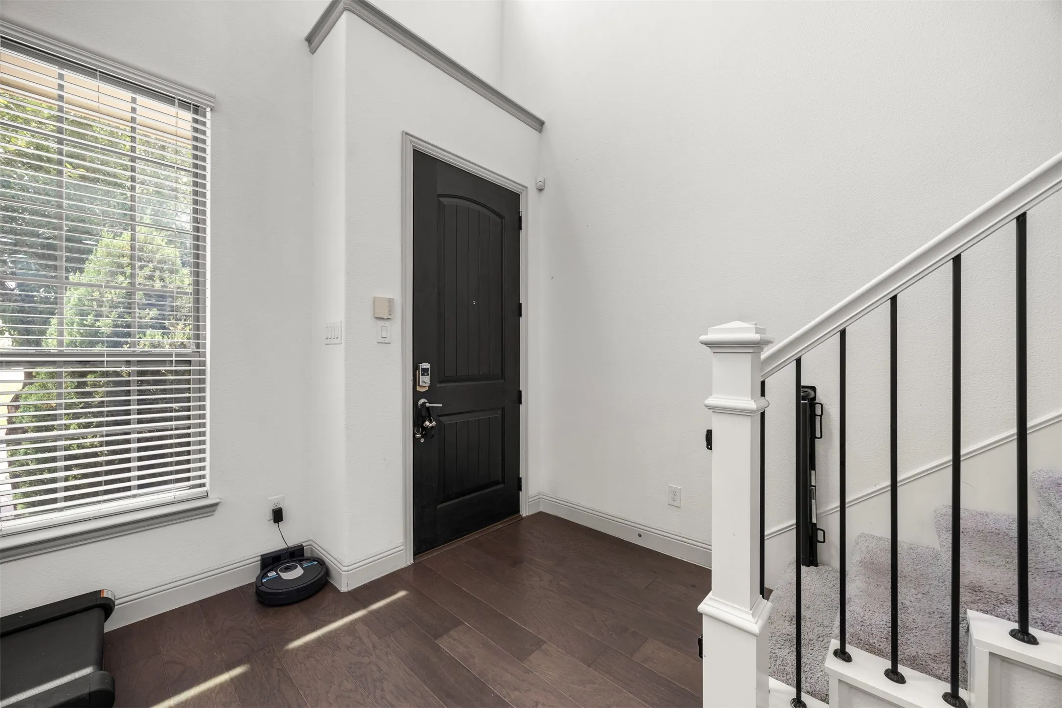 Entryway featuring a dark wood-finish door with an arched top panel, tall ceilings, and wood-finish flooring