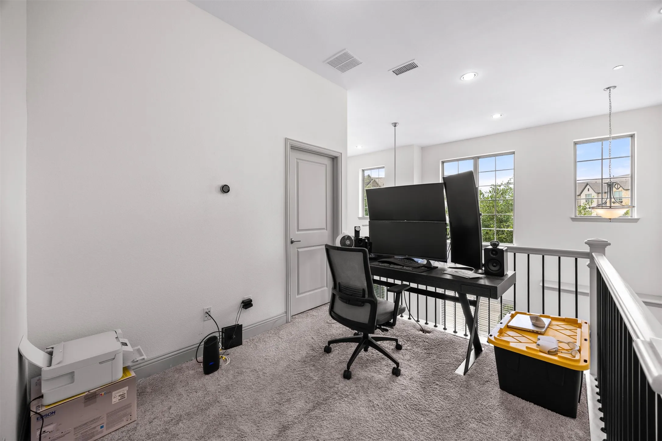 Loft area featuring light gray carpeting, a crisp white wall color, and a white door with dark hardware