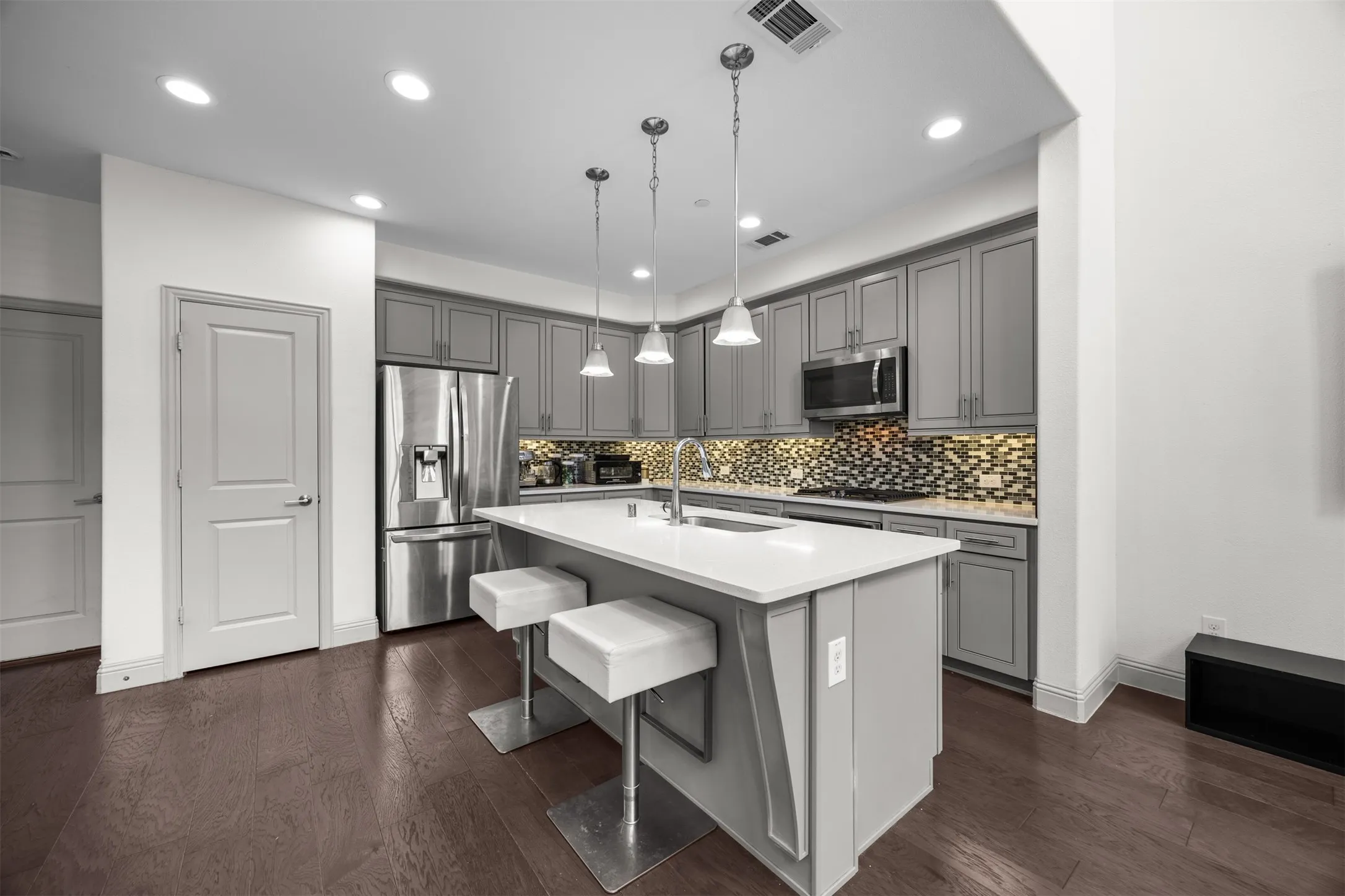 Kitchen featuring gray cabinetry, stainless steel appliances, a center island with countertop seating, and recessed lighting