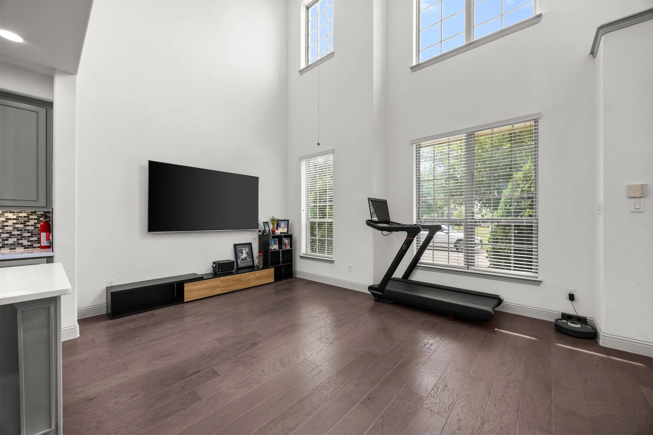 Spacious living area featuring high ceilings, wood-finish flooring, and ample natural light from multiple windows