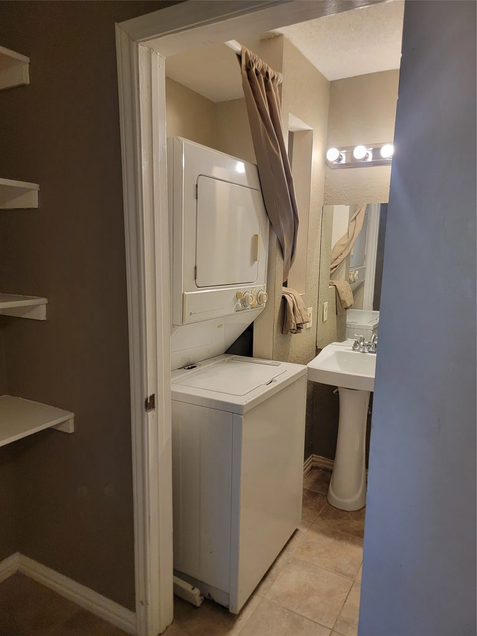 Compact laundry area featuring a stacked washer and dryer unit