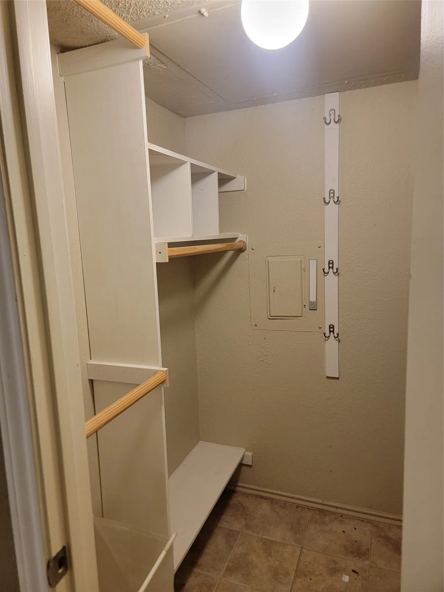 Interior closet featuring built-in shelving, hanging rods, and a coat rack with multiple hooks