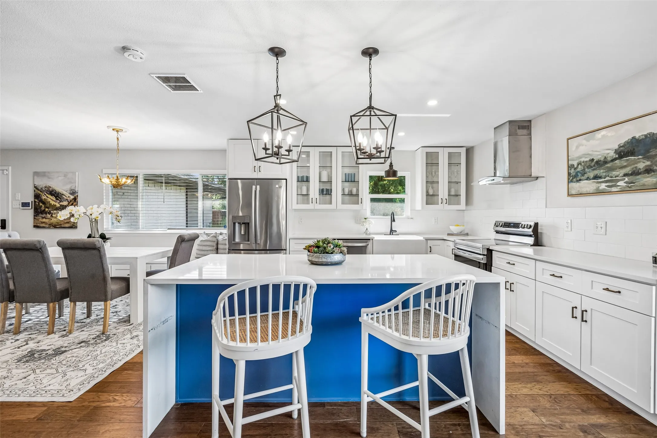 The kitchen and dining areas are attractively furnished with tailored cabinetry, sleek white work surfaces and a large island with stylish lantern lighting.  Of course, more large windows welcome the natural light!