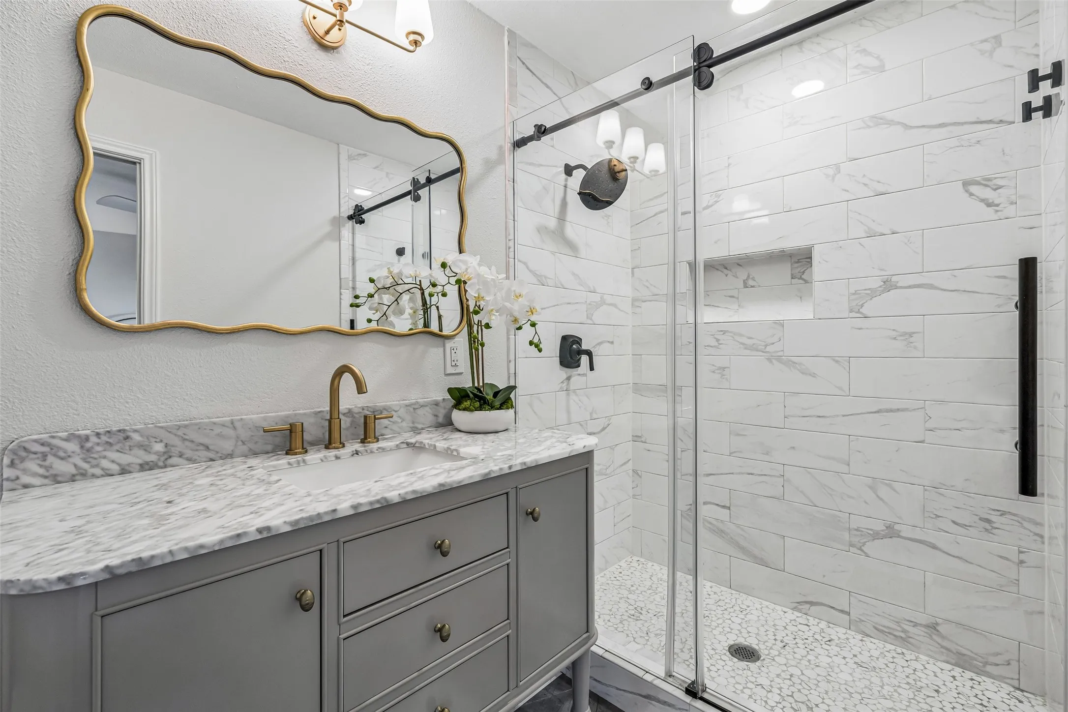 The primary bath has handsome cabinetry with ample storage. The spacious shower is smartly enclosed by a full wall stone lining.