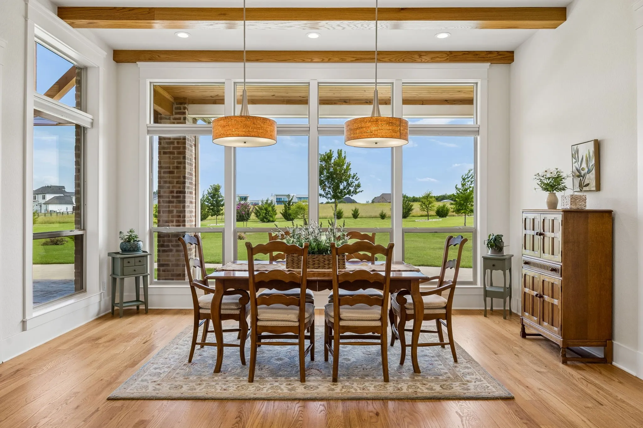 Spacious, sunlit dining room with exposed wood beams and large picture windows.