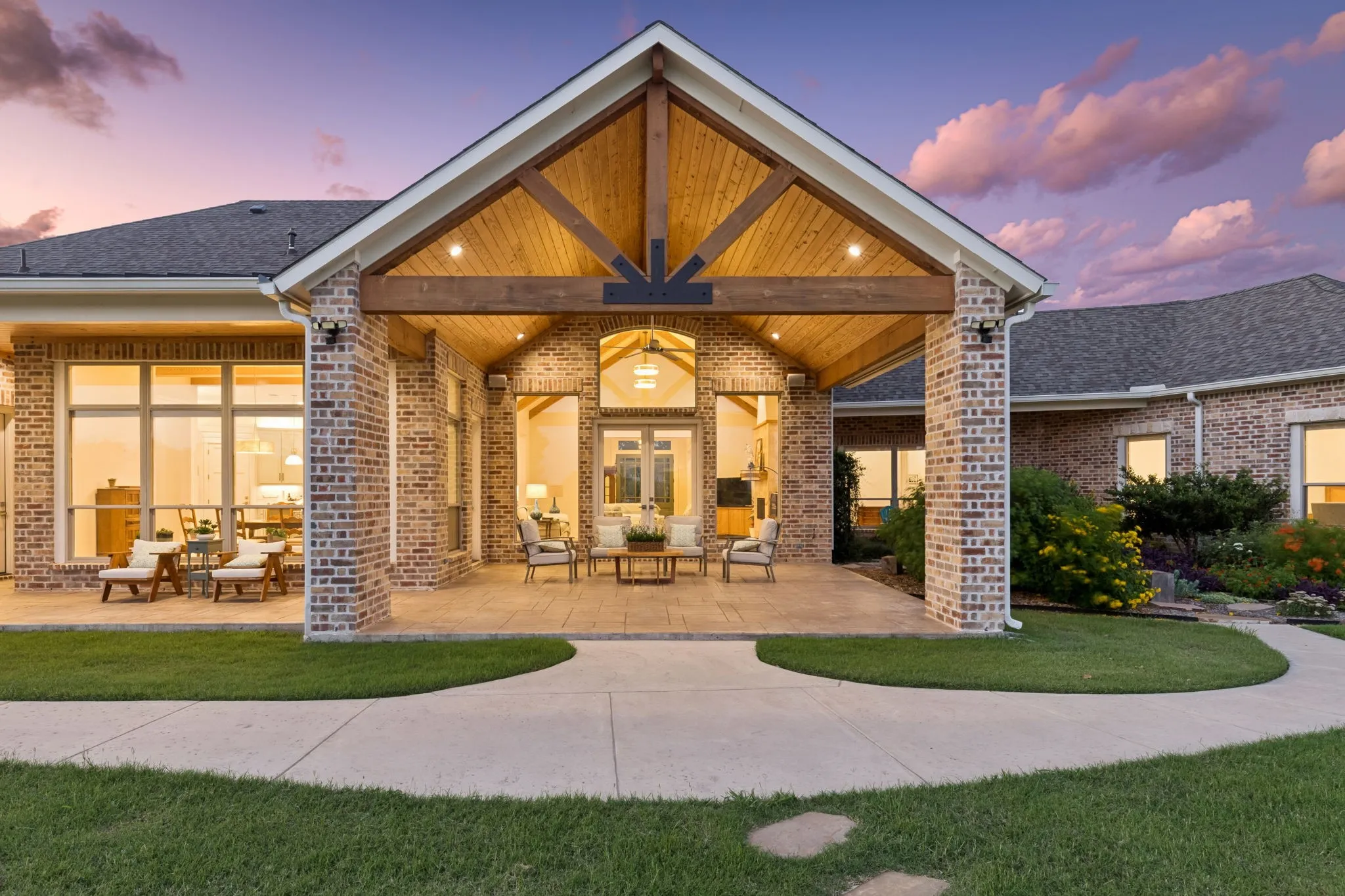 Expansive covered patio featuring a vaulted wood-paneled ceiling, exposed wood beams, and recessed lighting