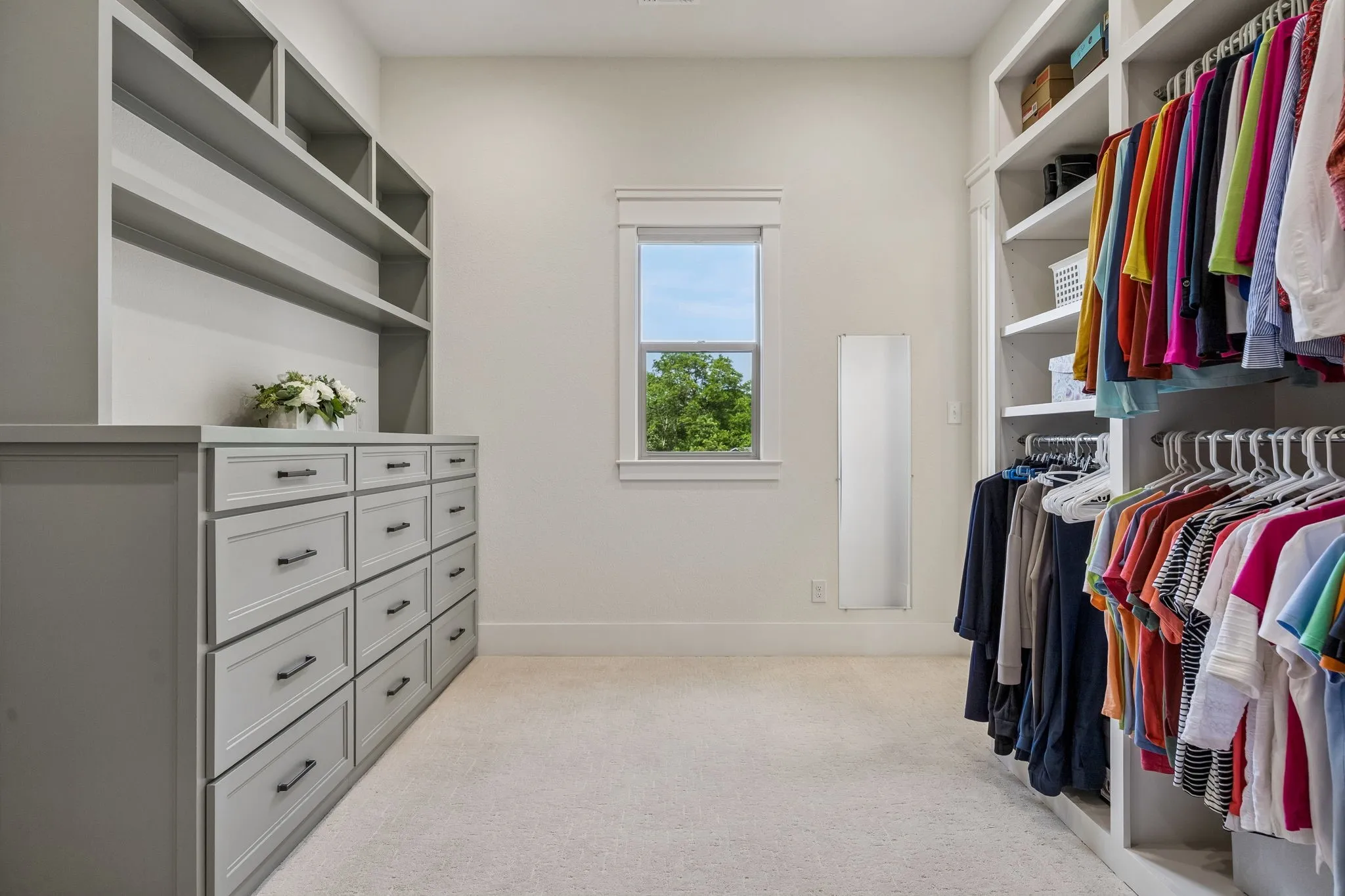 The impressive custom primary closet features built-in shelving, integrated drawer storage, and natural light.