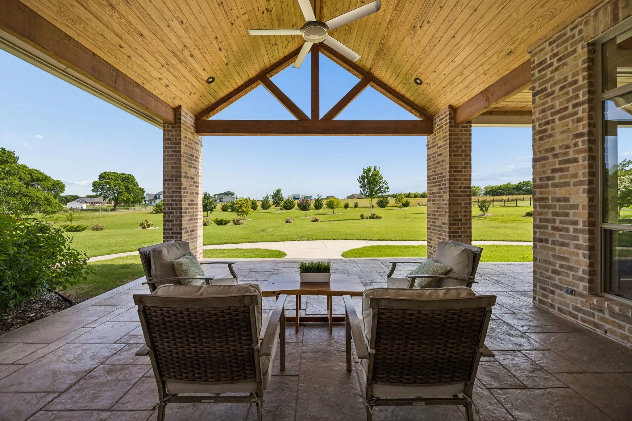 Large outdoor living area with a stunning vaulted natural pine ceiling with exposed beams, ceiling fan, recessed lighting, and peaceful views.