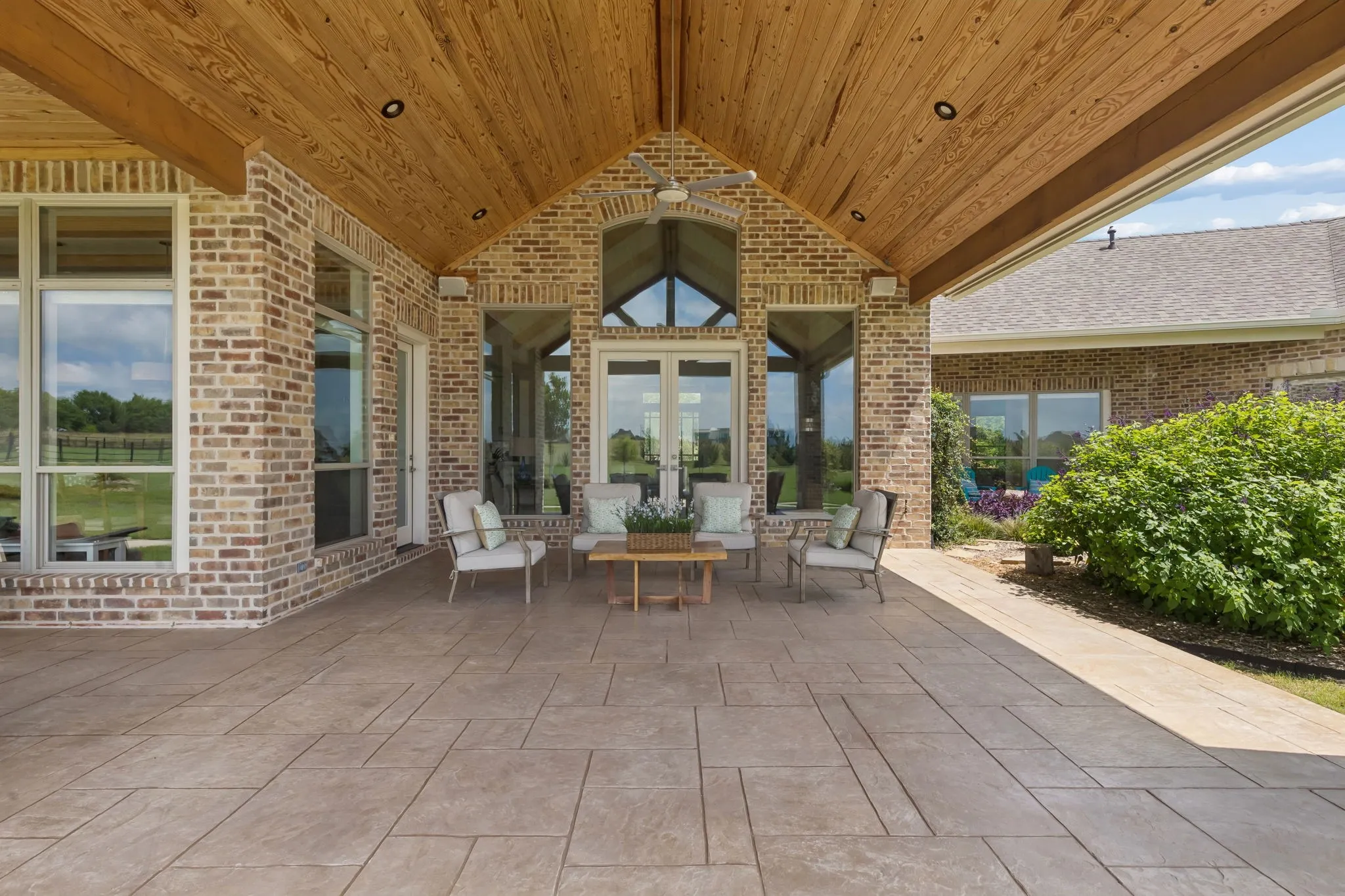Large outdoor living area with a stunning vaulted natural pine ceiling, exposed beams, and surrounded by year-round texture and beauty.