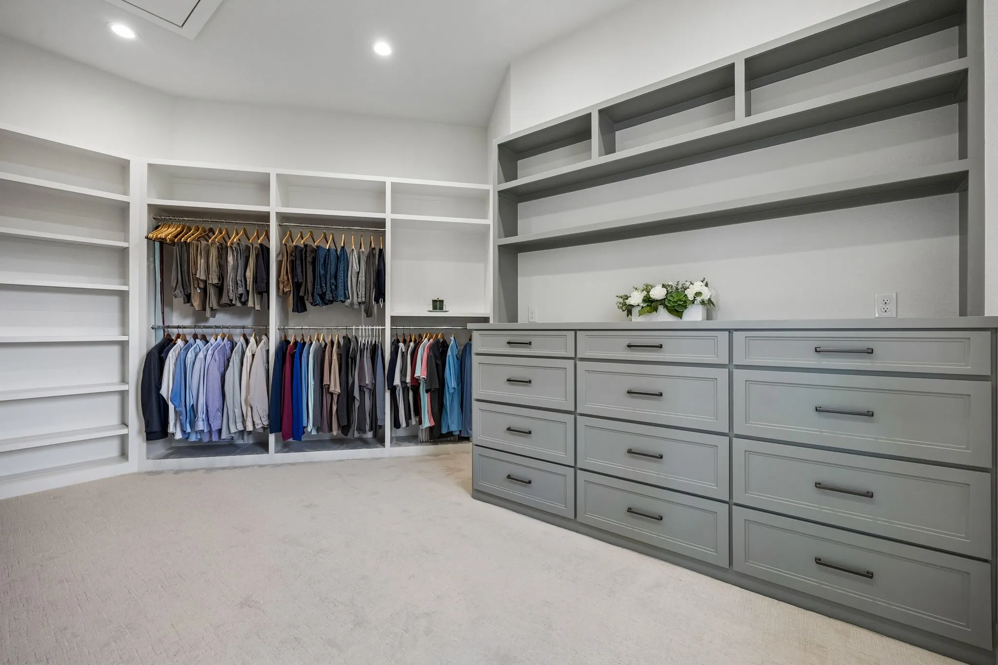 The impressive custom primary closet features built-in shelving, integrated drawer storage, and natural light.