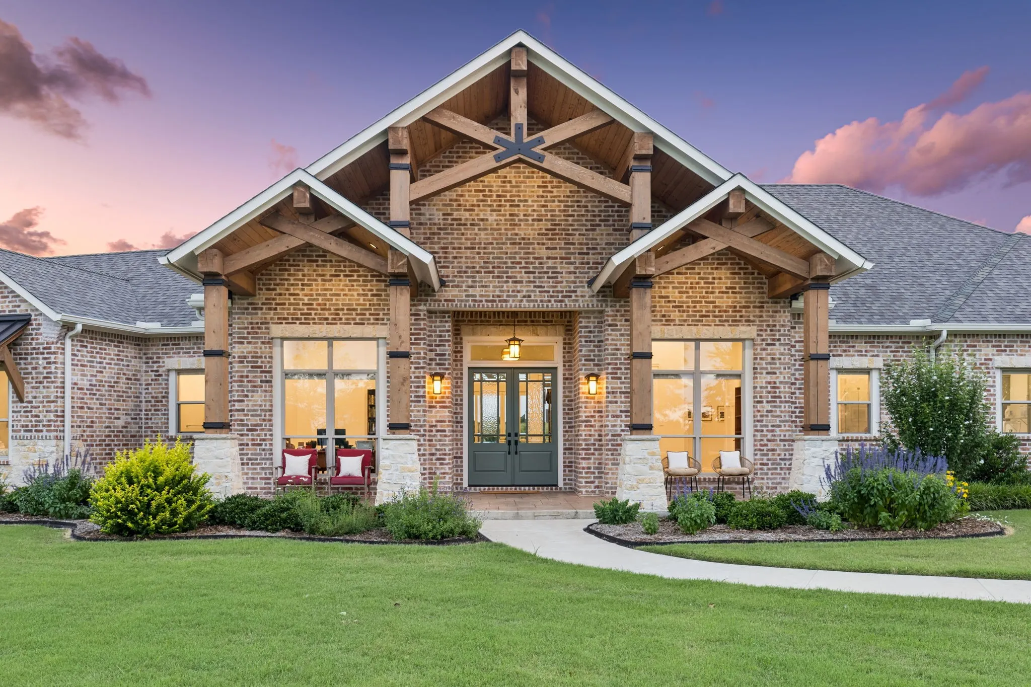 Brick exterior, exposed wood beams, and cedar columns encased in stone frame a deep, covered front porch that welcomes you inside, where walls of windows immediately capture picturesque views of the remarkable grounds.