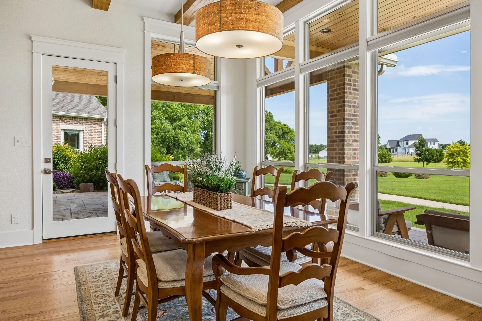 Spacious, sunlit dining room with exposed wood beams and large picture windows with exterior access.