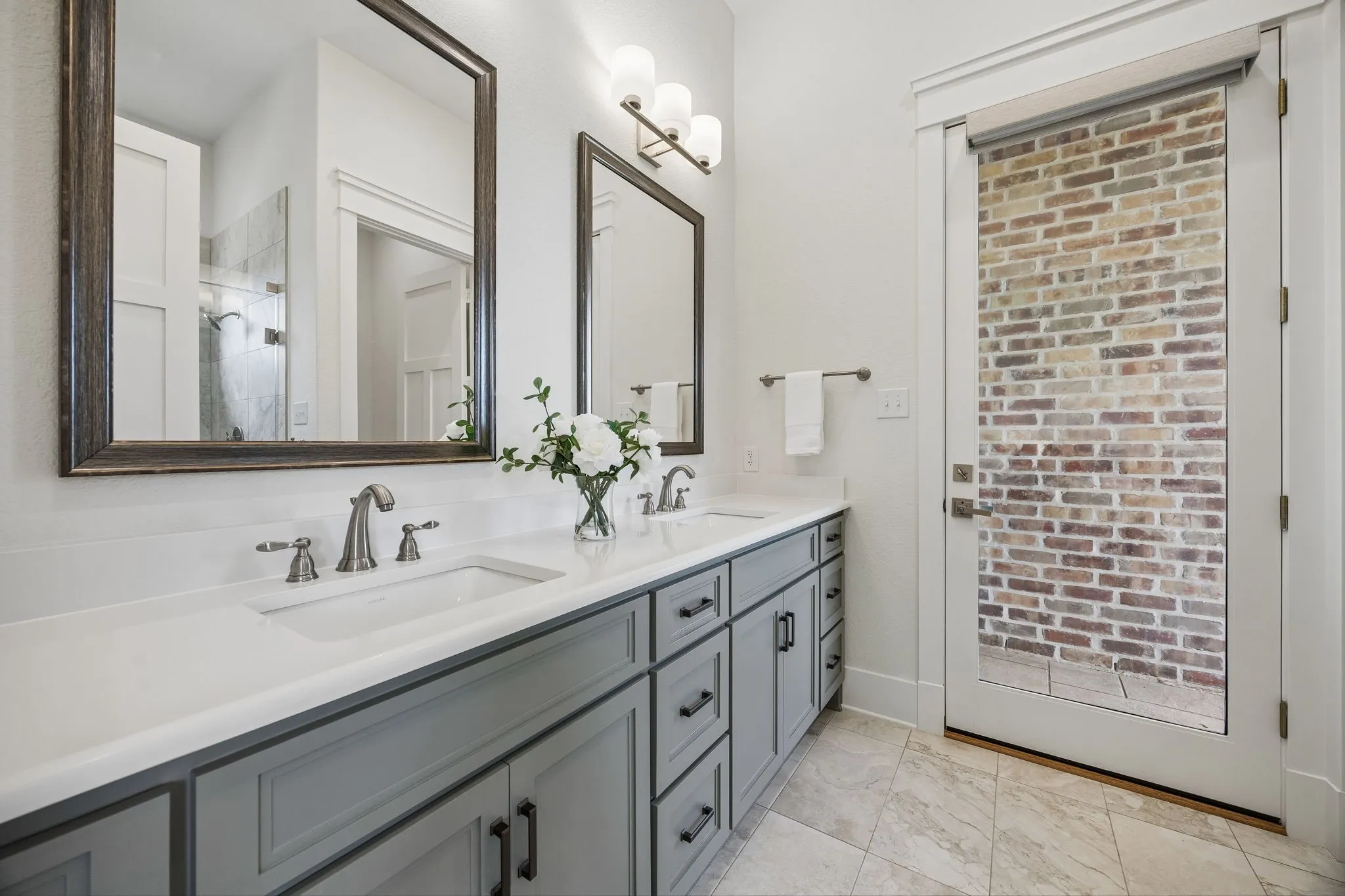 Guest suite full bath with dual sinks, oversized walk-in shower, and exterior access to outdoor living.