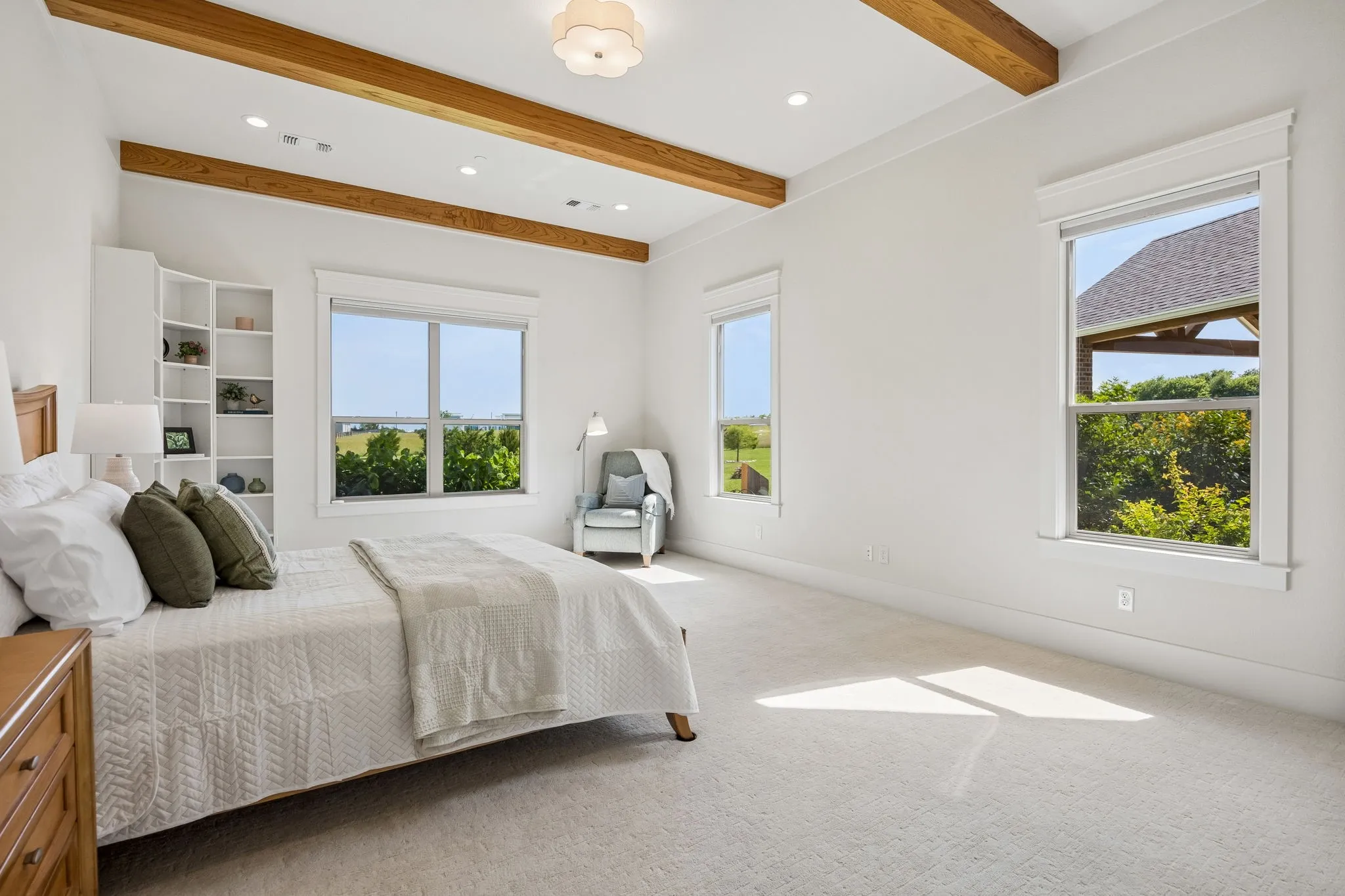 A gallery-style hallway leads to the primary suite, tucked away with exposed wood beams, tranquil views, luxurious spa bath, and large custom closet.