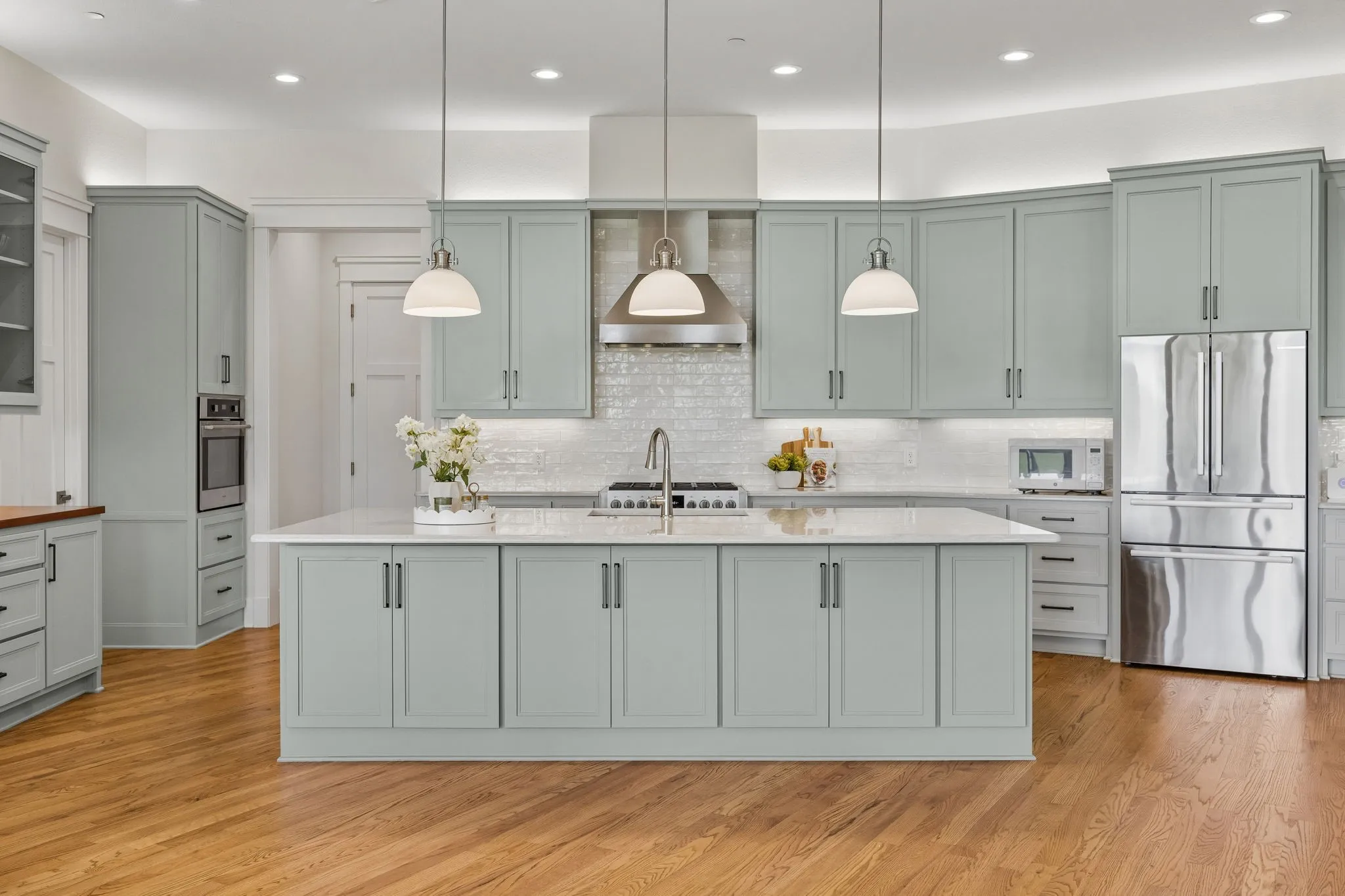 The gourmet kitchen is fully equipped with a 6-burner commercial-grade range and hood, custom shaker cabinetry, white subway tile backsplash, built-in hutch, walk-in pantry, and large center island with breakfast bar seating.