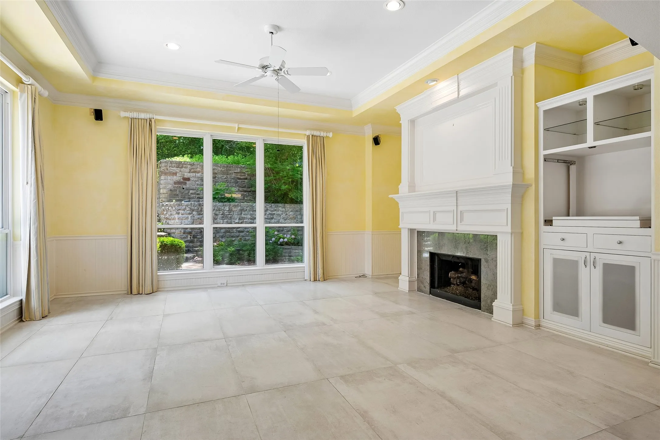 Light and bright living room with cove ceiling, windows on two walls, custom drapes, fireplace, built ins.