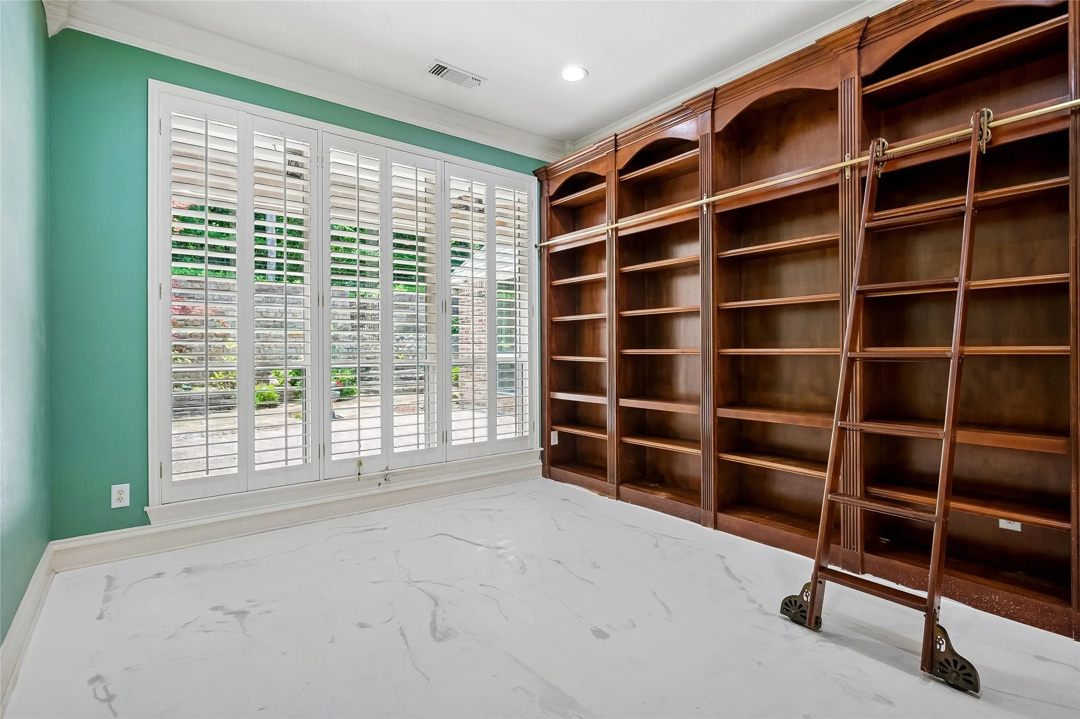 Wall of windows with shutters overlooks patio. Custom floor.