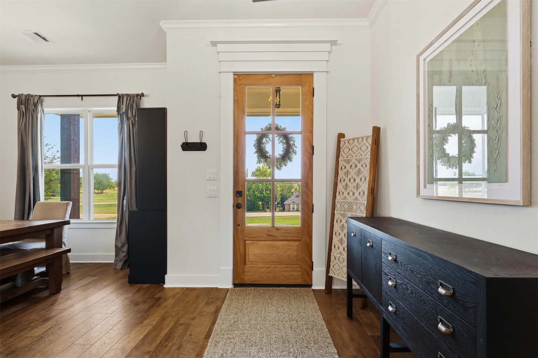 Entryway featuring a natural wood-finish door with glass panels, wood-finish flooring, and crown molding