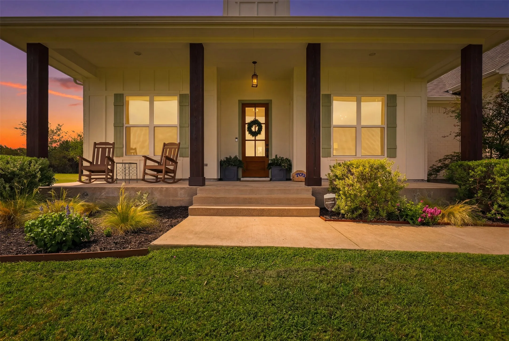 Inviting front porch featuring substantial wood-finish columns, a solid wood entry door, and decorative green shutters