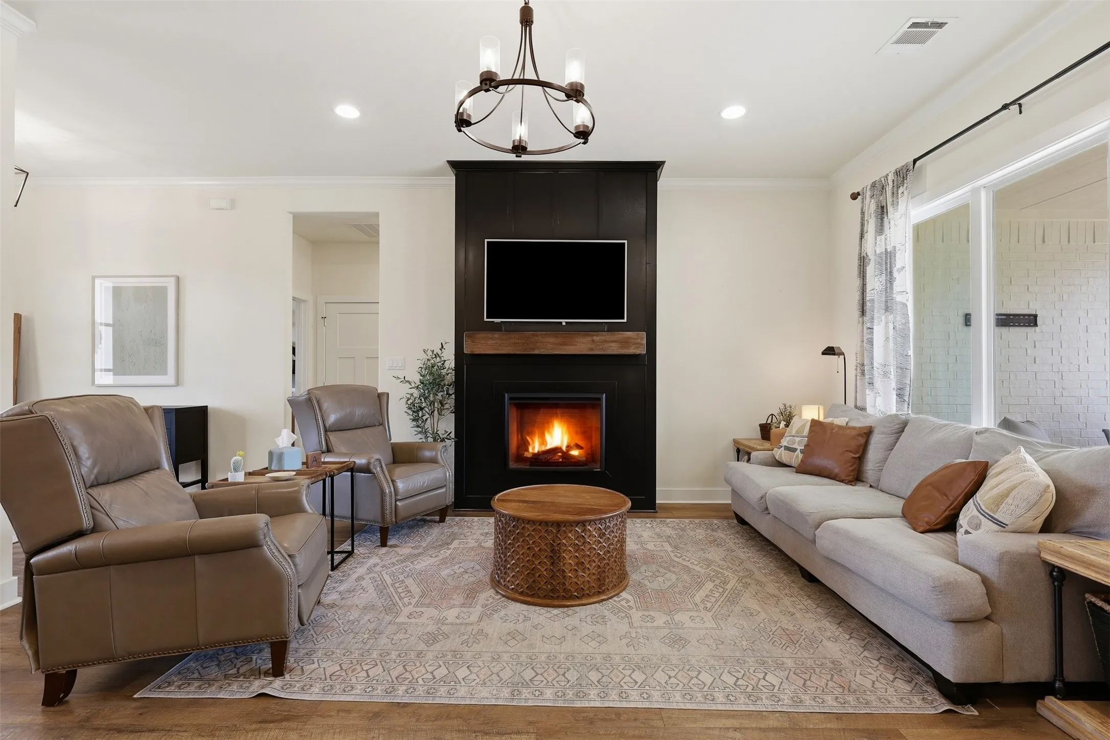 Living area featuring a floor-to-ceiling black fireplace surround with a wood mantel, recessed lighting, and wood-finish flooring