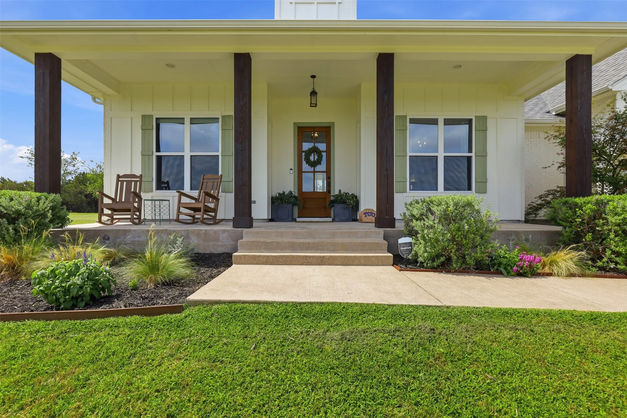 Inviting front porch featuring substantial wood-finish columns, a solid wood front door, and decorative window shutters
