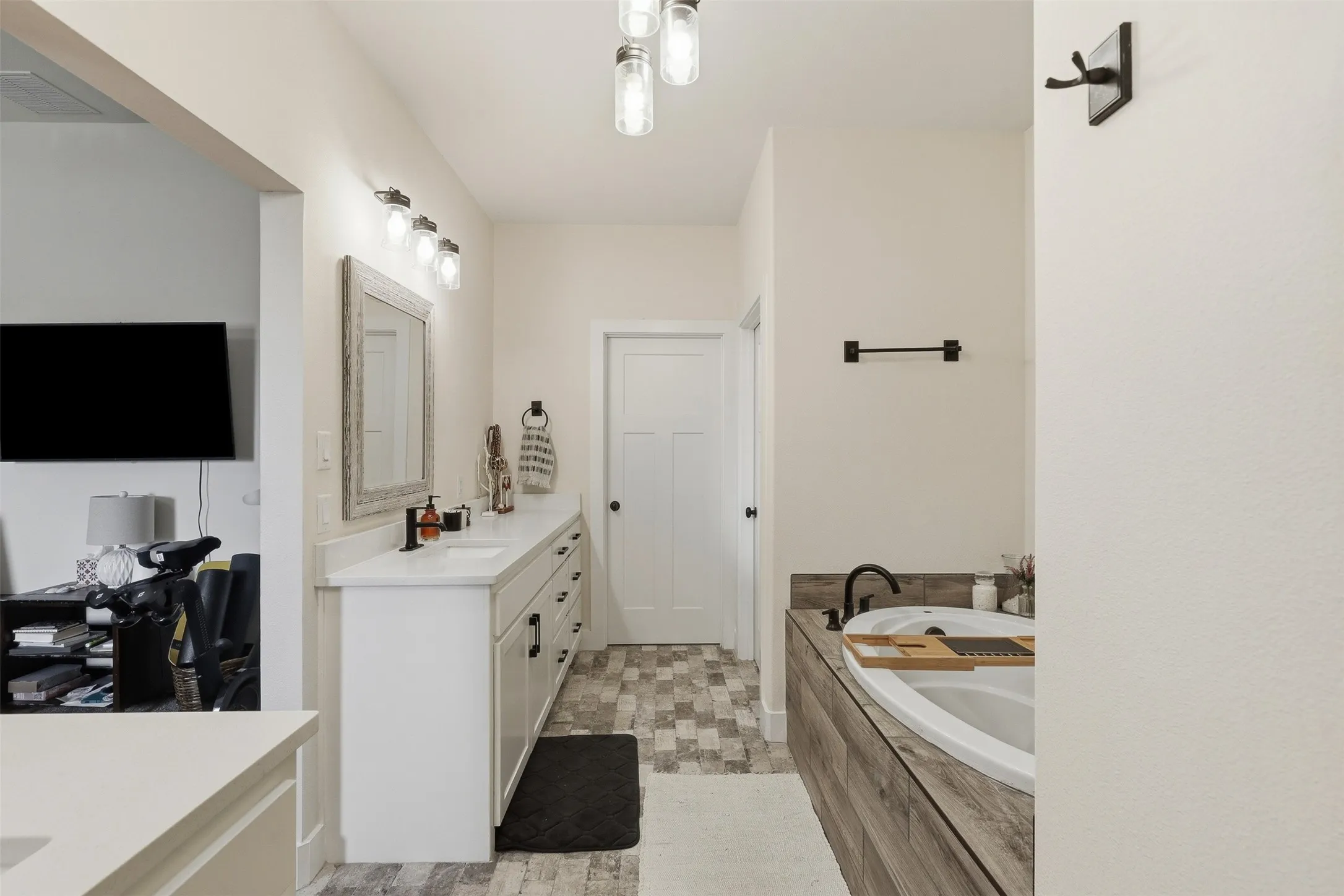 Dual sink vanity with white cabinetry, a light-toned countertop, and matte black hardware