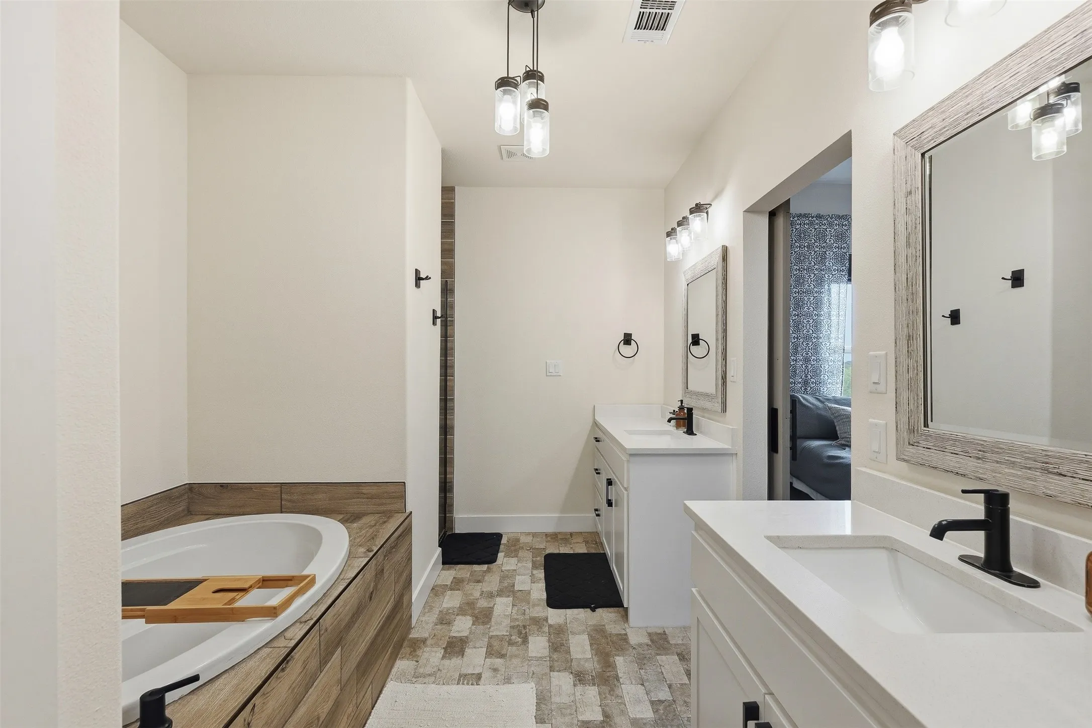 Spacious bathroom featuring dual vanities with white countertops, integrated sinks, and matte black fixtures