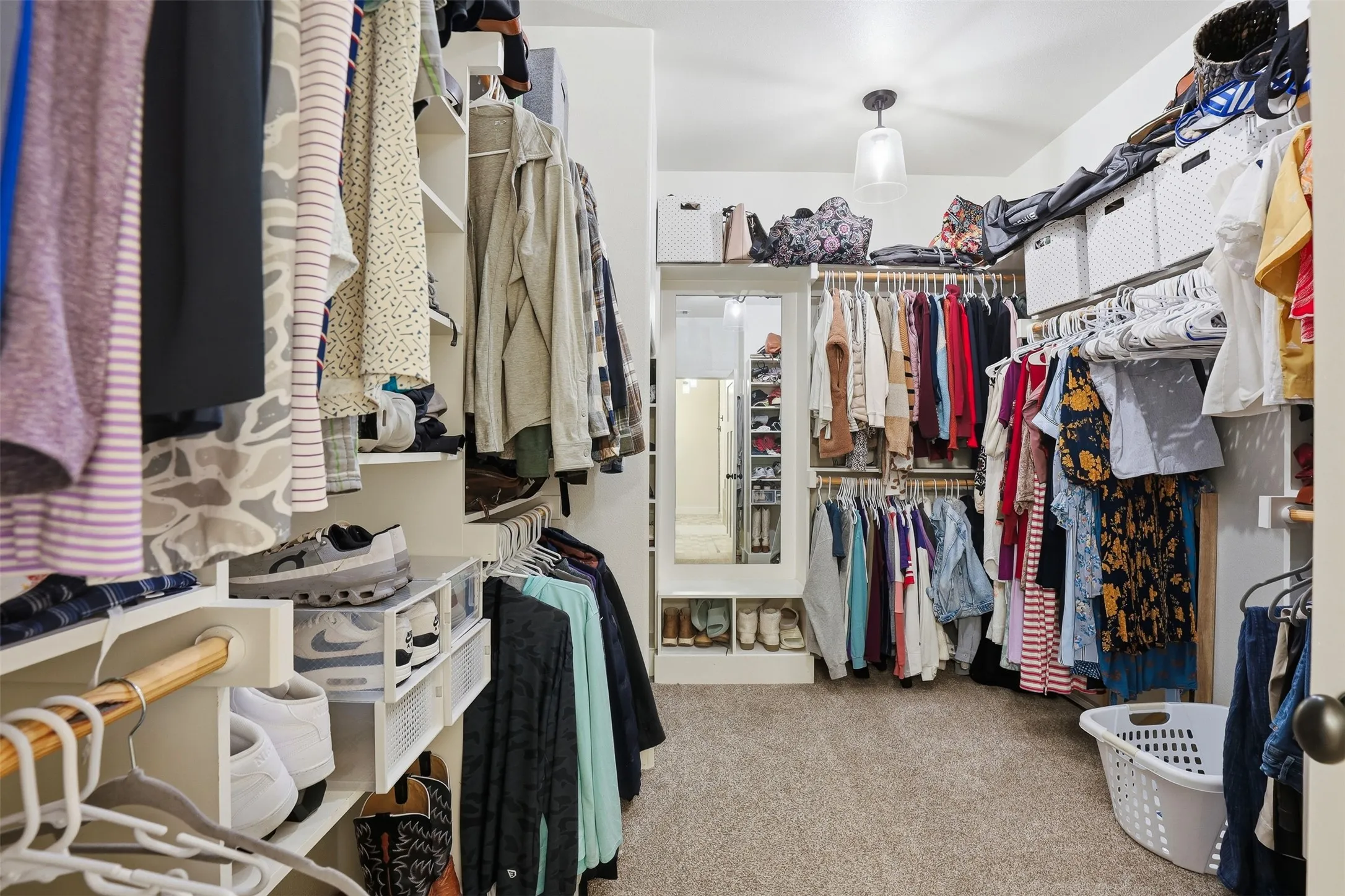 Walk-in closet featuring built-in shelving, multiple hanging rods, carpet flooring, a full-length mirror, and overhead lighting