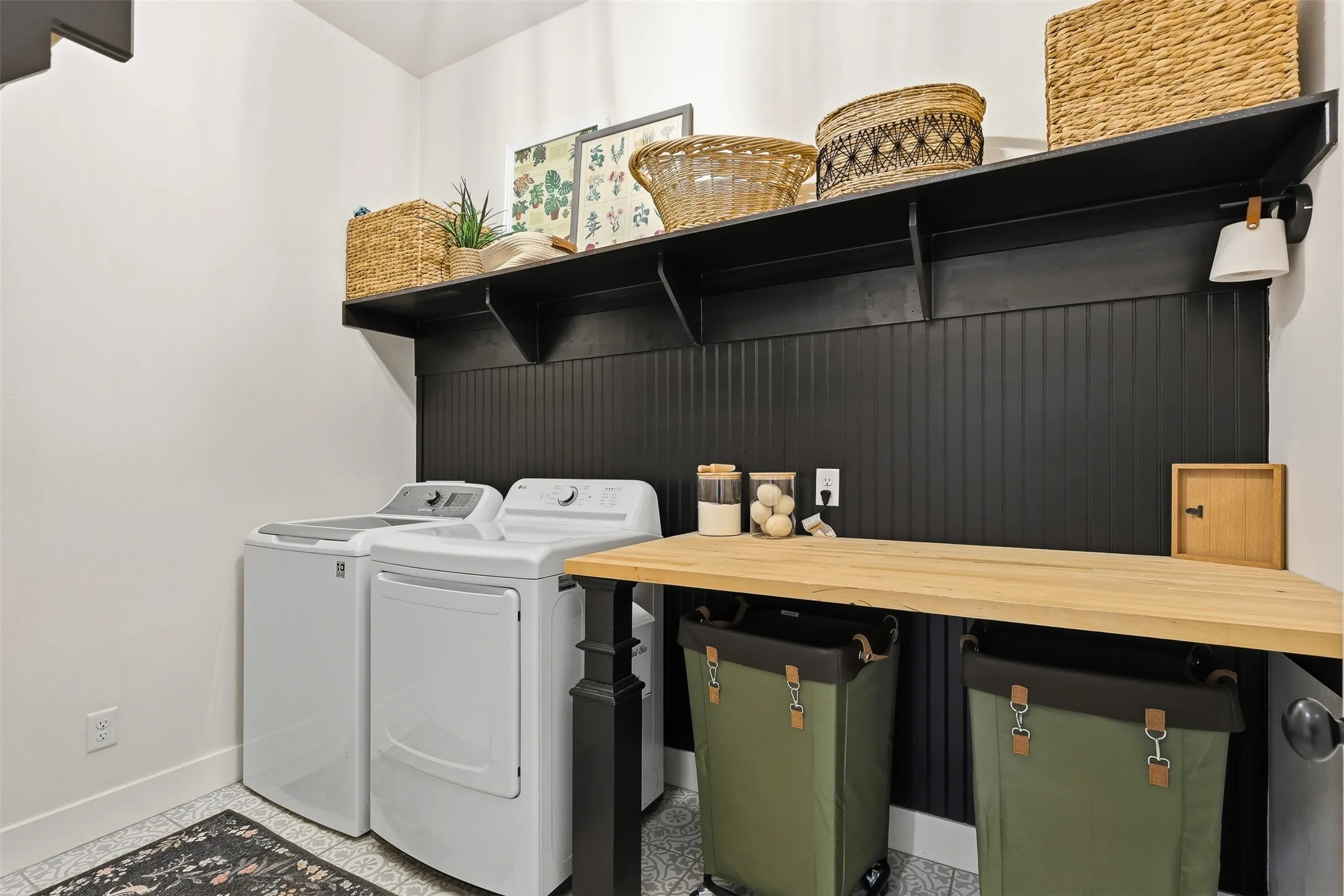 Dedicated laundry area featuring a butcher block countertop, black beadboard accent wall, and built-in shelving