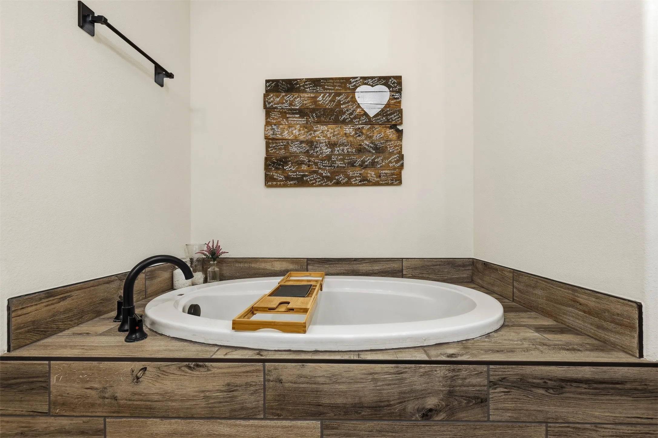 Built-in soaking tub featuring wood-finish surround, contemporary matte black fixtures, and clean white walls