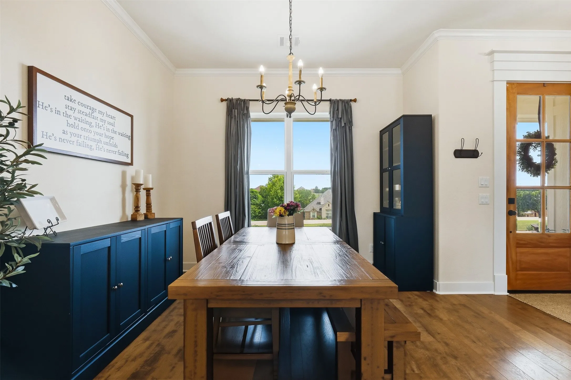 Dining area featuring wood-finish flooring, a large window, a chandelier, and a wood-panel entry door