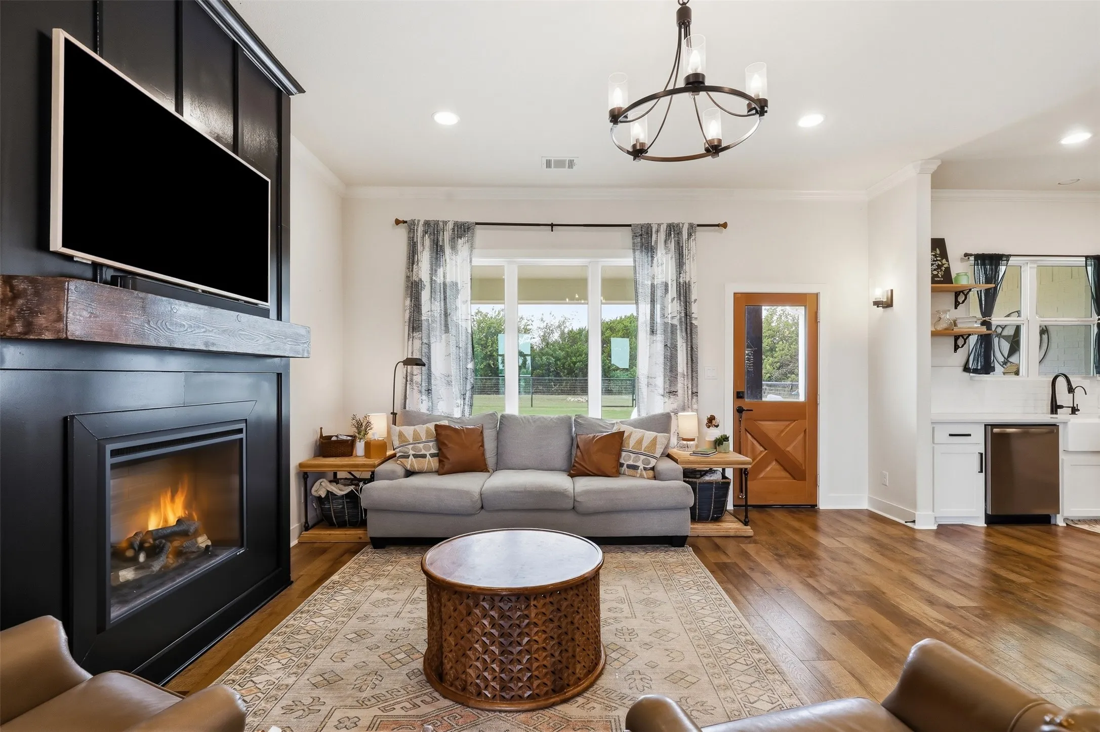 Spacious living area featuring rich wood-finish flooring, a modern fireplace with a dark mantel, and recessed lighting