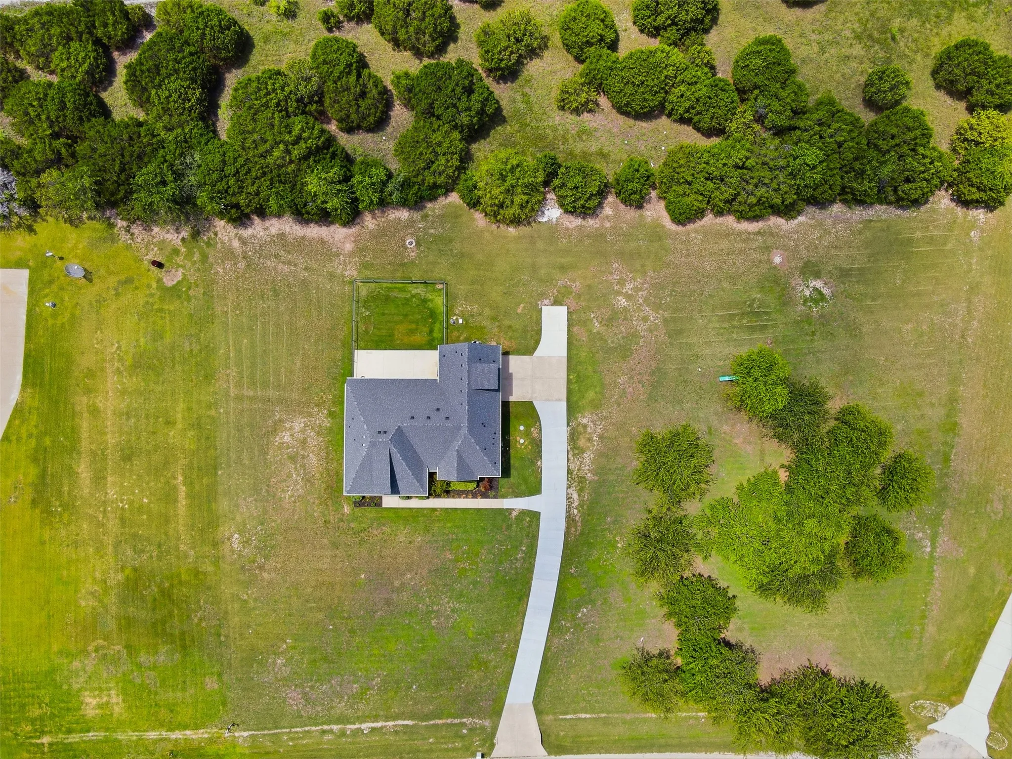 Single-story residence on a spacious lot featuring a gray shingled roof and a paved driveway