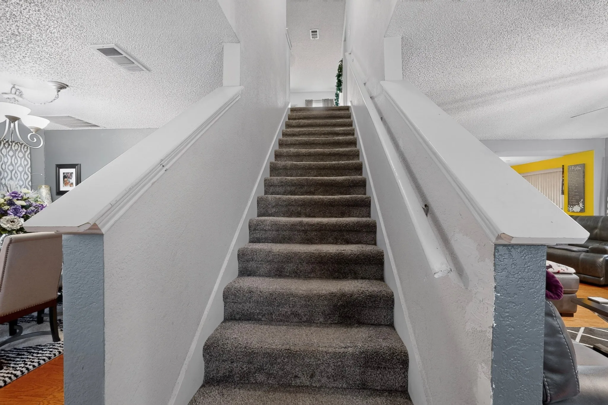 Carpeted staircase with white painted handrails