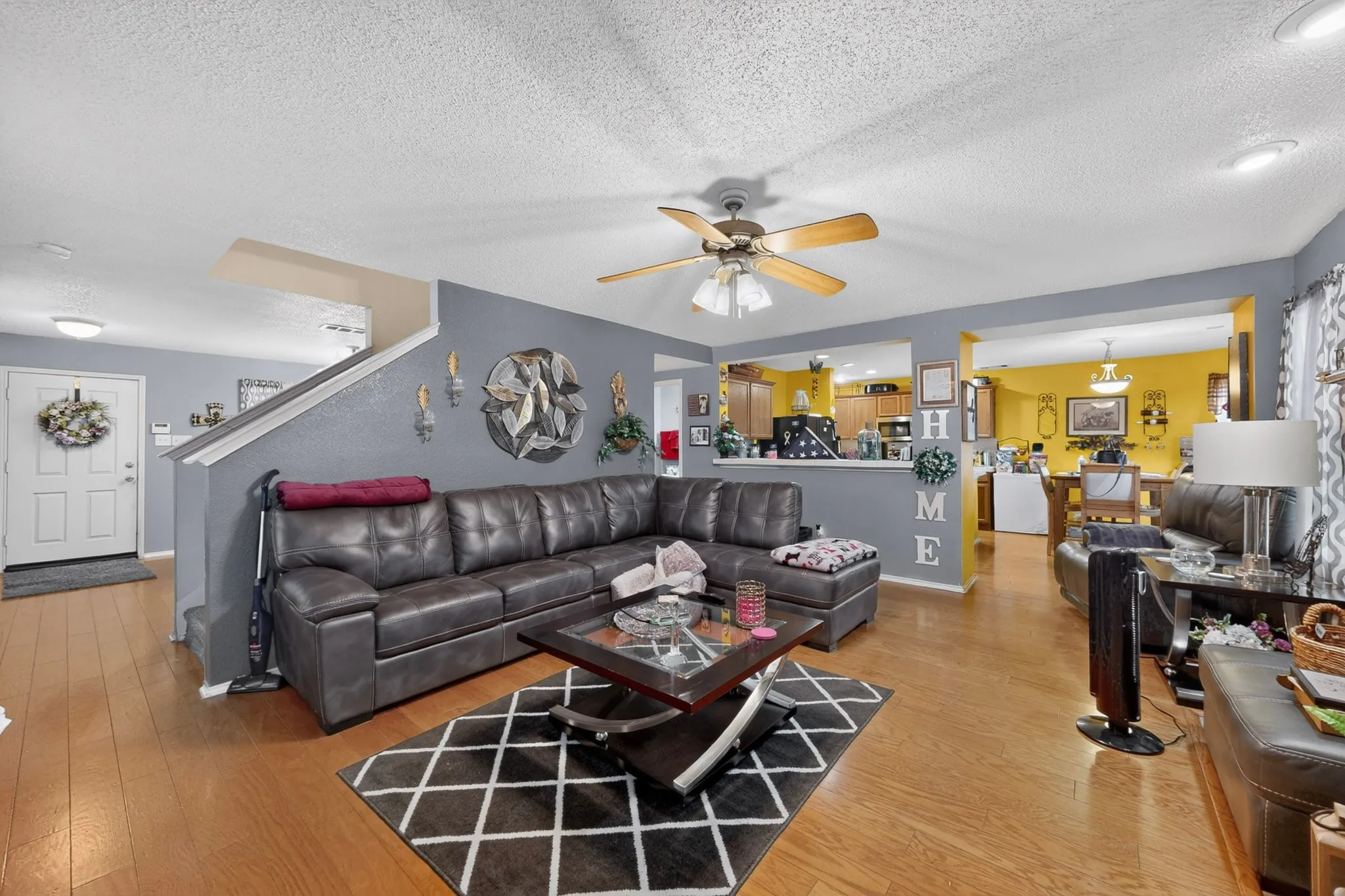 Open-concept living space featuring wood-finish flooring, a contemporary ceiling fan, and a half-wall partition