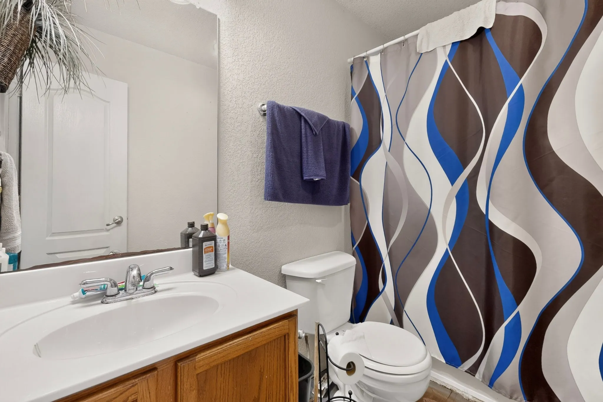 Bathroom featuring a wood-finish vanity with a single basin sink and a chrome faucet