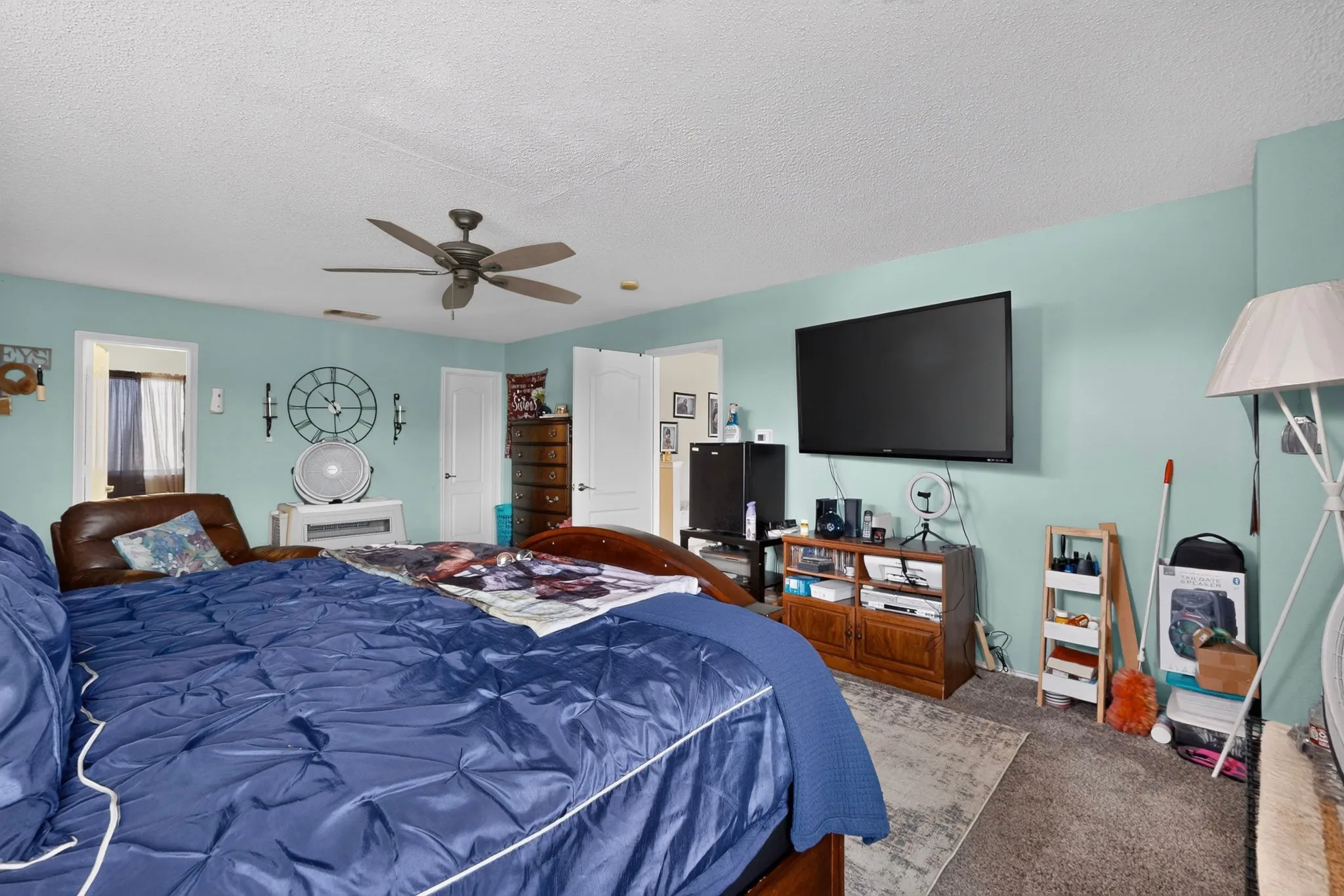 Spacious room featuring light teal walls, a ceiling fan, and carpet flooring