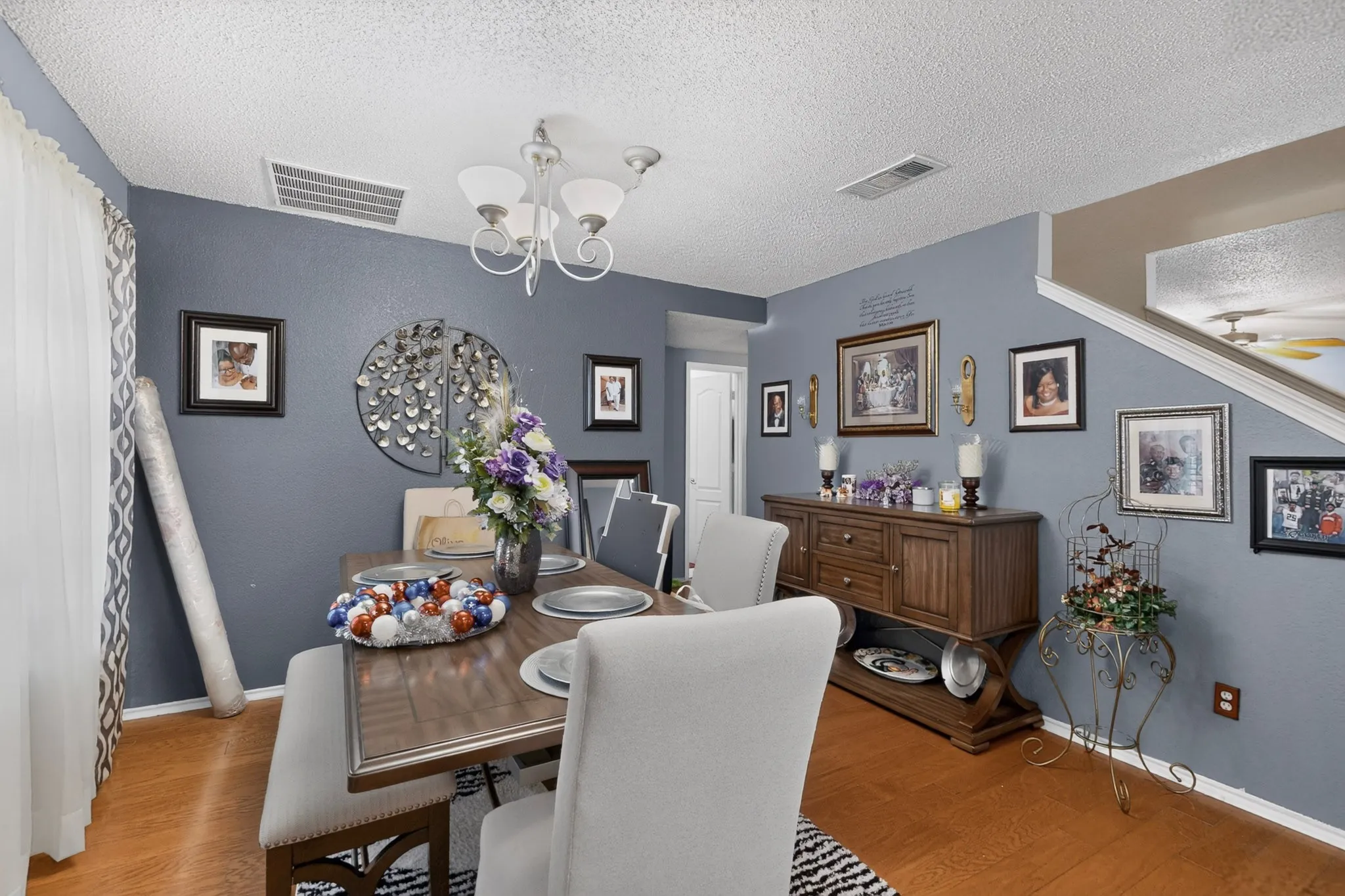 Dining area featuring wood-finish flooring, a contemporary chandelier, and a built-in staircase