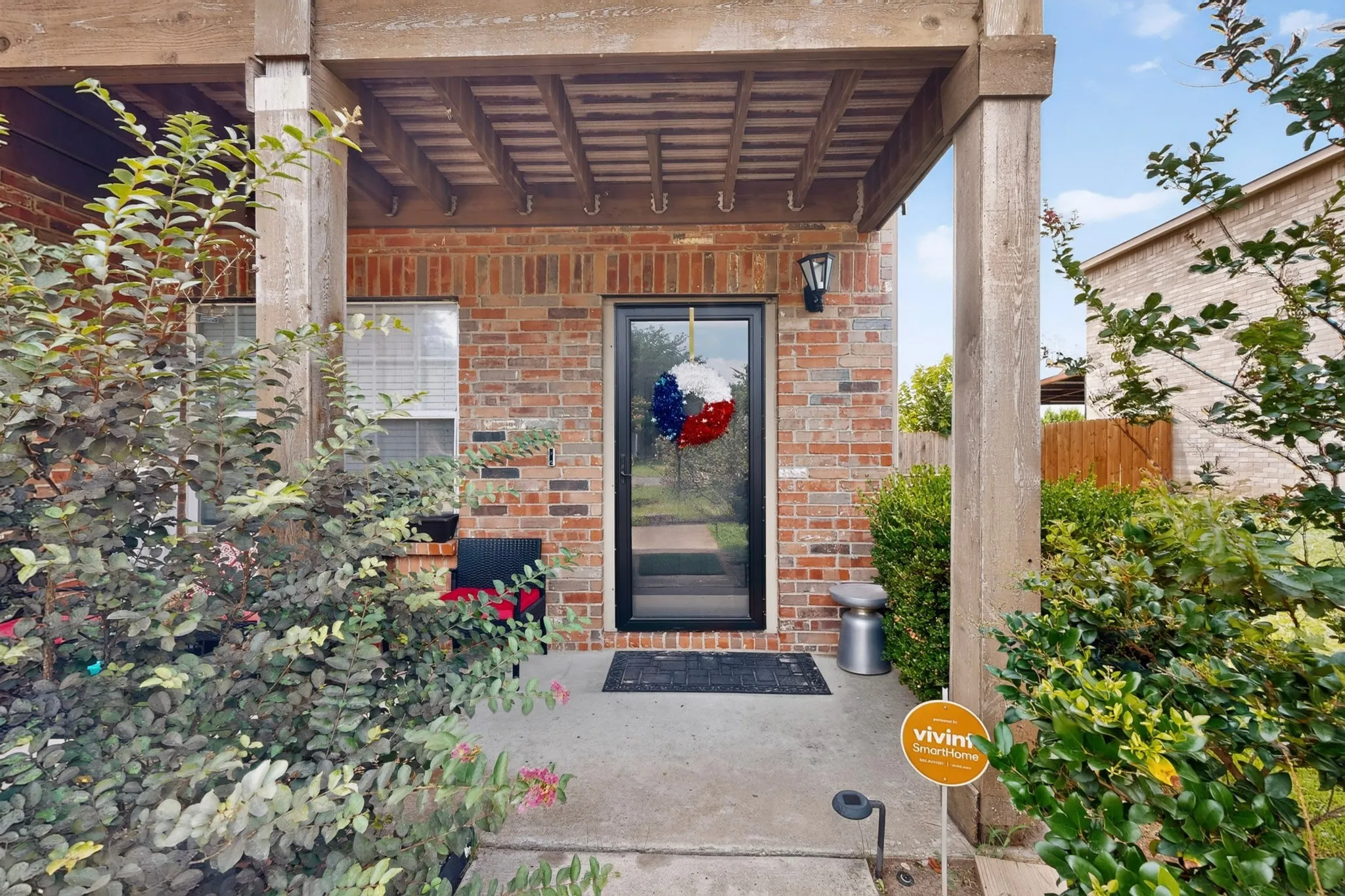 Brick exterior featuring a covered entry, wood-finish columns, and a concrete patio