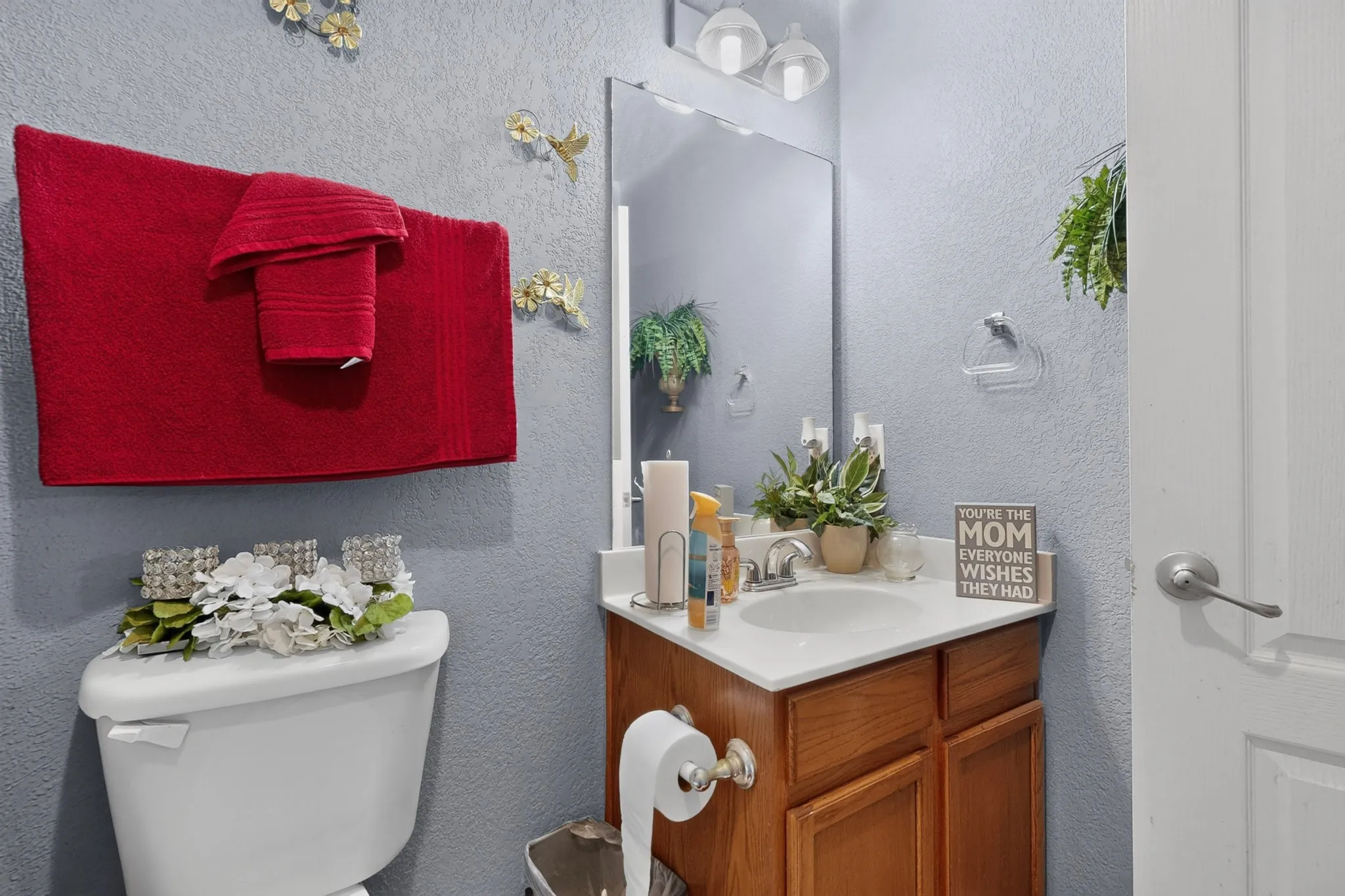 Powder room featuring a single vanity with a white countertop, wood-finish cabinetry, and a wall-mounted mirror