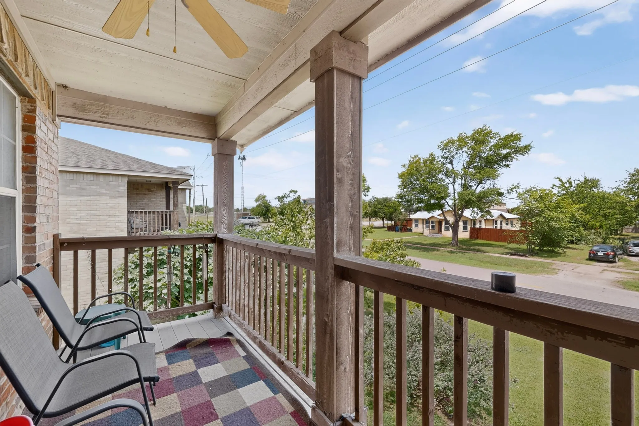 Covered porch with wood-finish railings and a ceiling fan