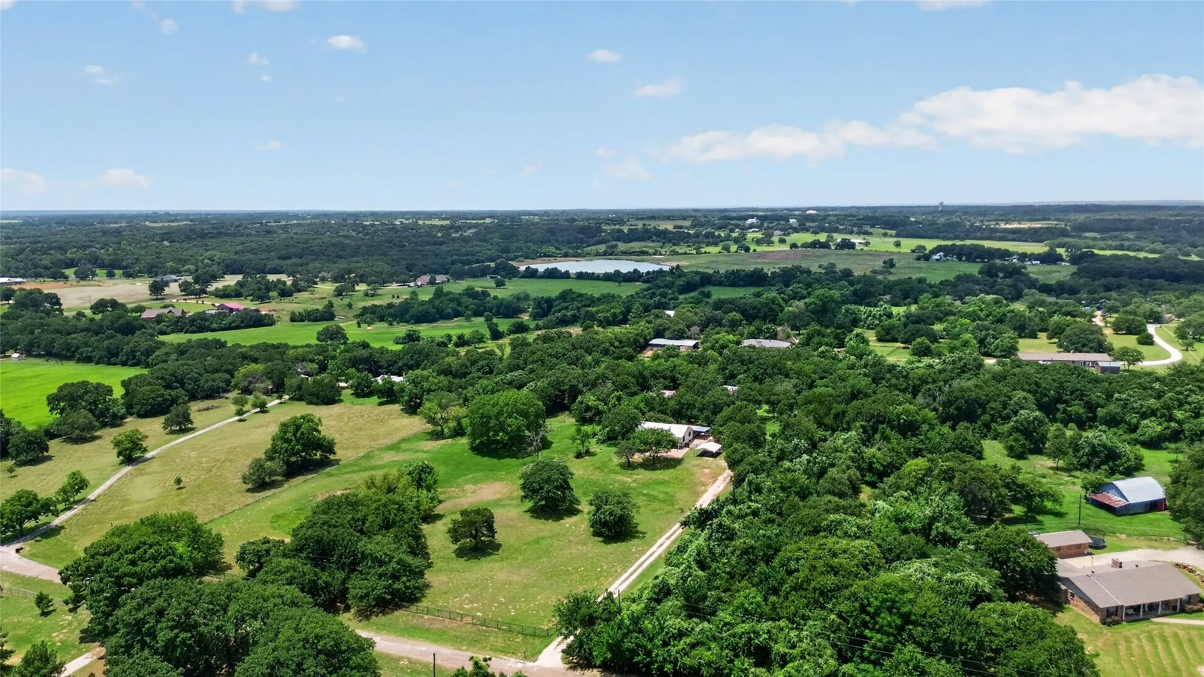 Expansive aerial landscape featuring lush green fields and scattered mature trees