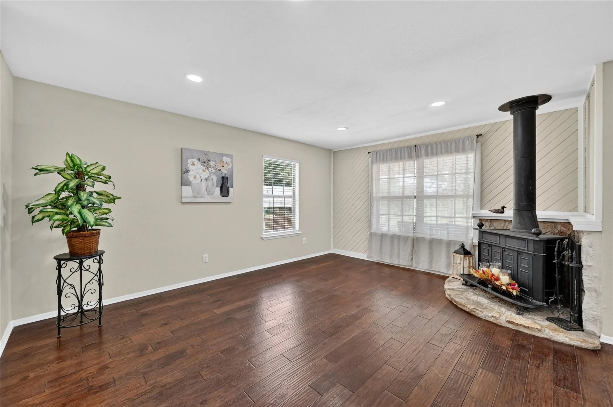 Warm wood-finish flooring, neutral colors with a corner fireplace on stone hearth